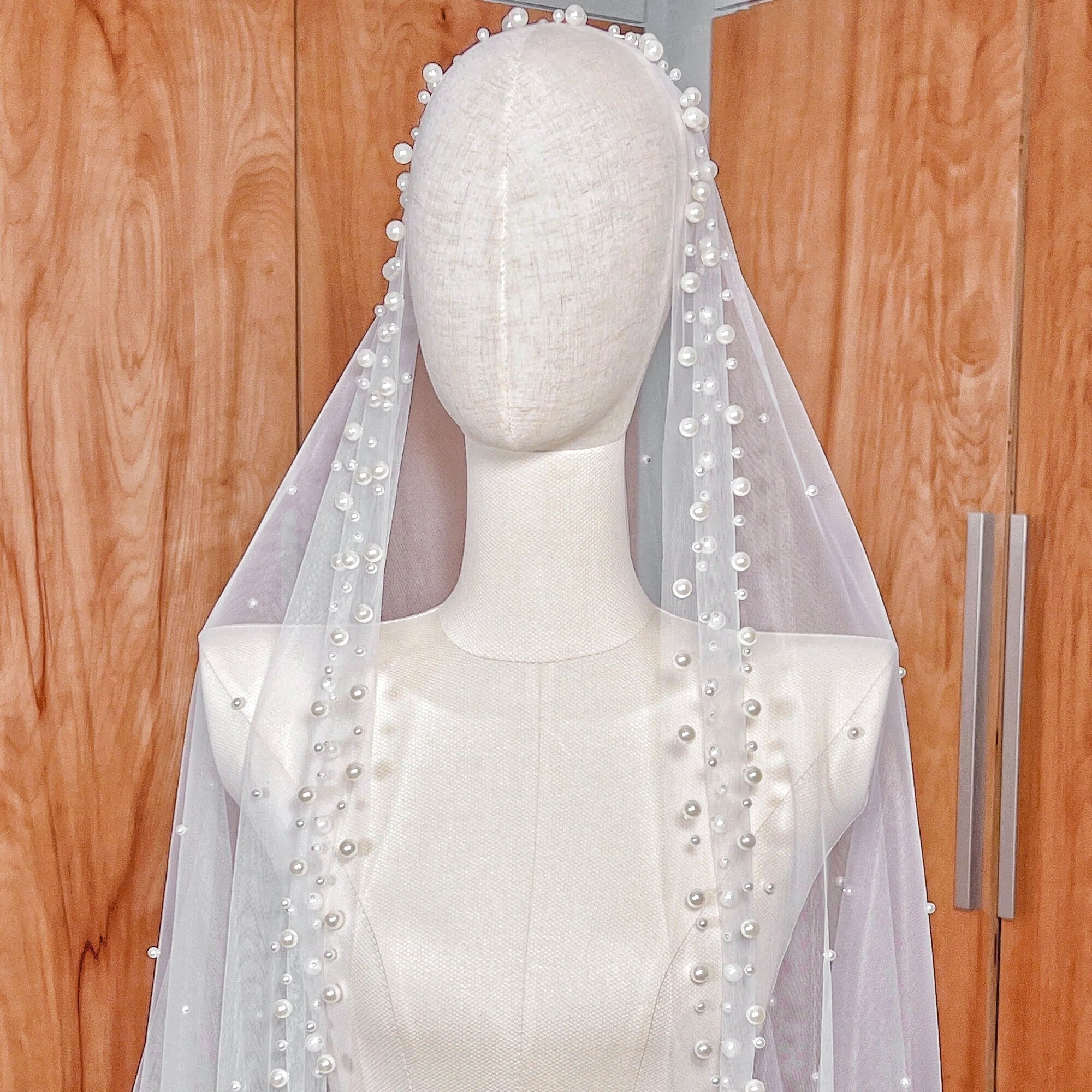 Side profile of the scattered pearl edge mantilla wedding veil in cathedral length shown on a mannequin to display the drape.