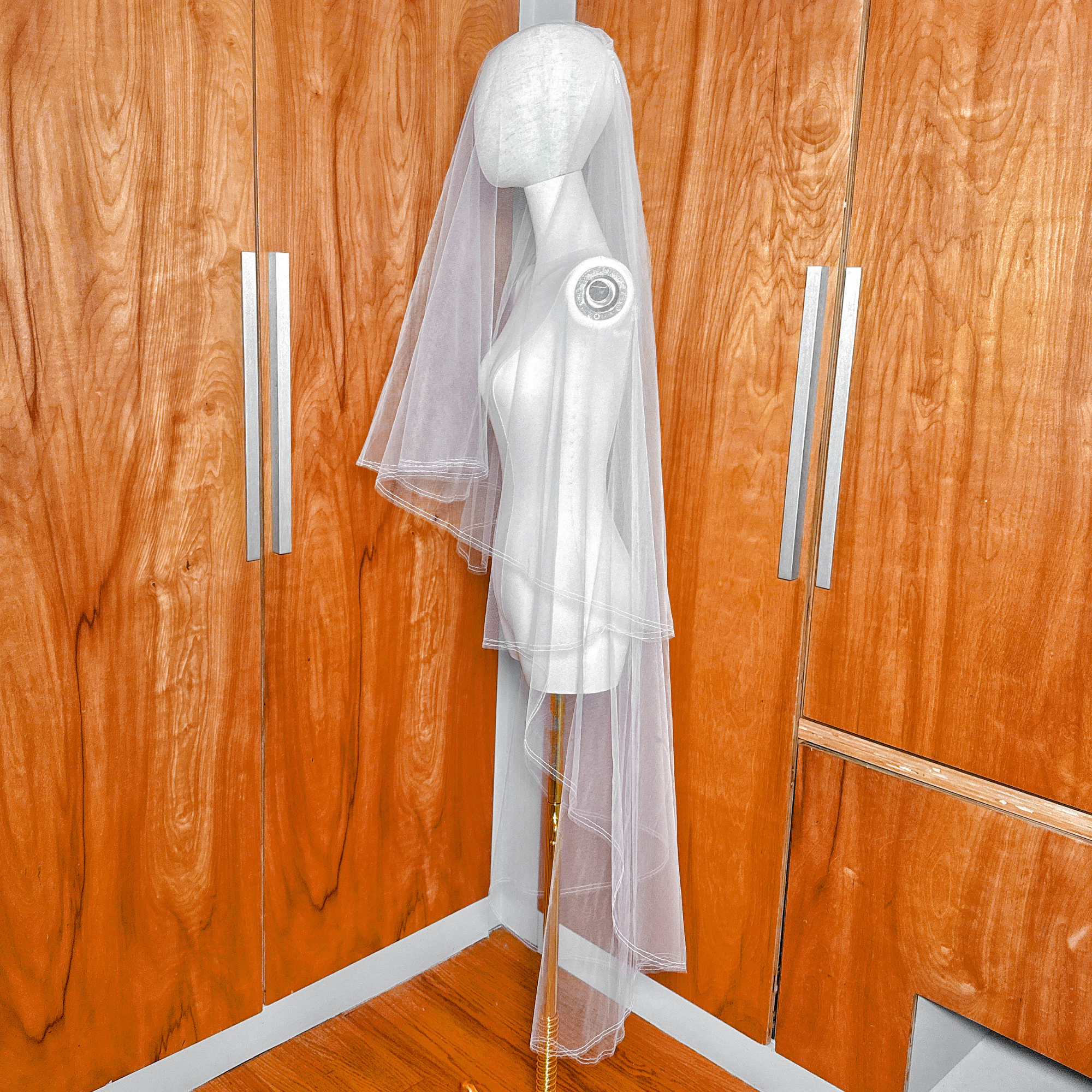 Side profile of a mannequin wearing a two tier wedding veil with a pencil edge and blusher in waltz length.
