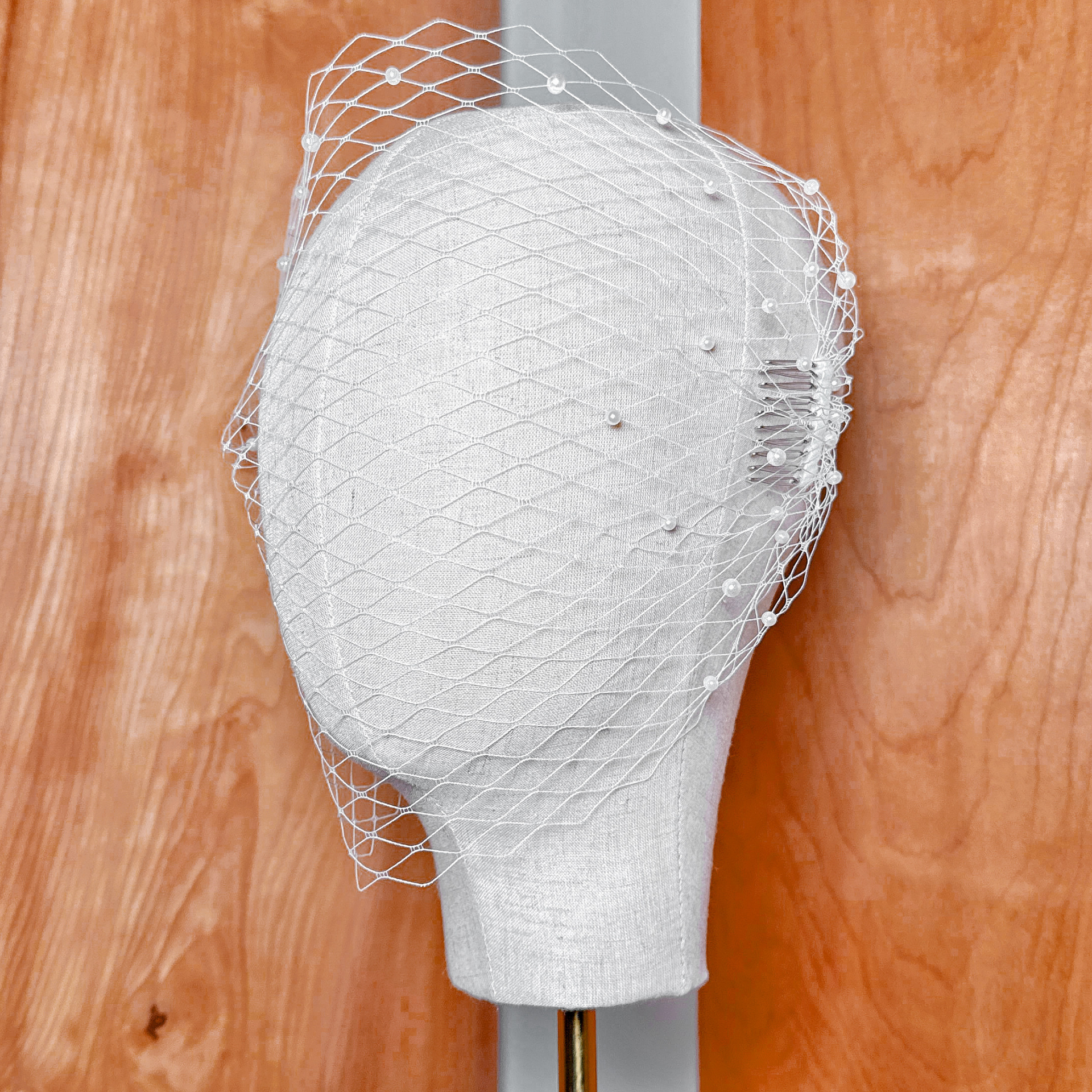 Side profile of a vintage-style bandeau birdcage wedding veil with pearls showcasing the gathered netting drape.