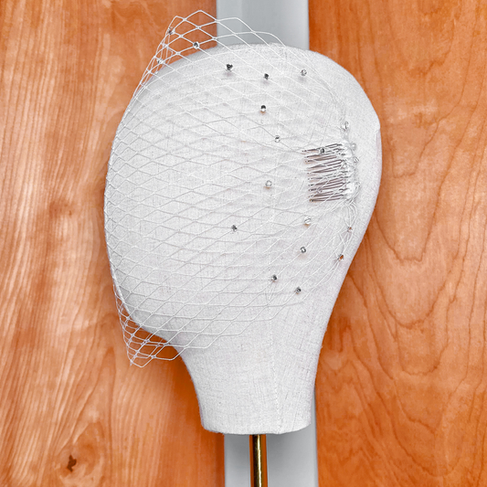 Side view of a white bandeau birdcage wedding veil featuring scattered rhinestones.
