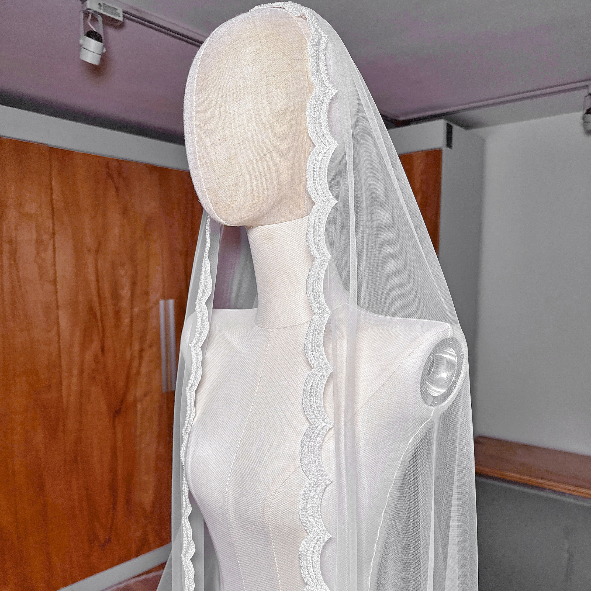 Side profile of a beaded mantilla wedding veil in royal cathedral length demonstrating how the sheer tulle and beaded trim drape over the shoulders.