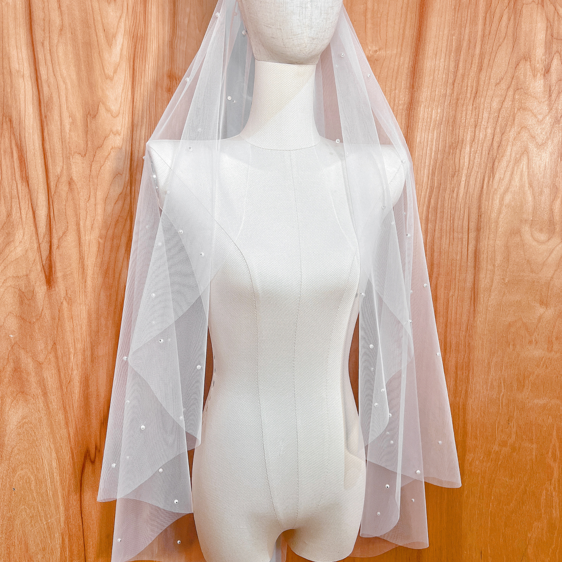 Side view of a fingertip length cascading scattered pearl wedding veil showing the sheer tulle drape.