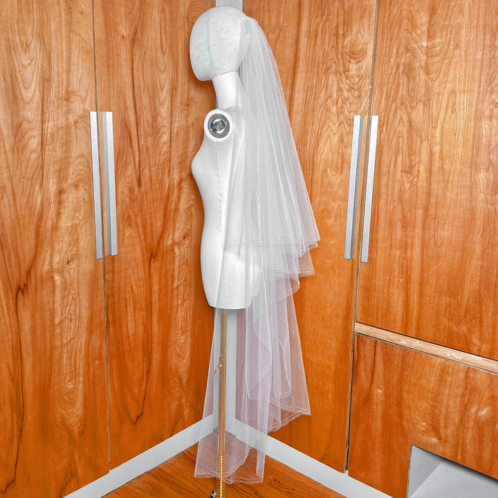 Side profile view showing the drape and waltz length of a two tier wedding veil with rose gold edge.