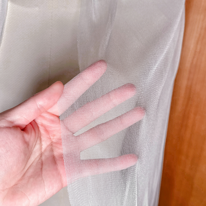 Macro close-up of the fine weave and translucent finish of a high-quality silk tulle fingertip veil.