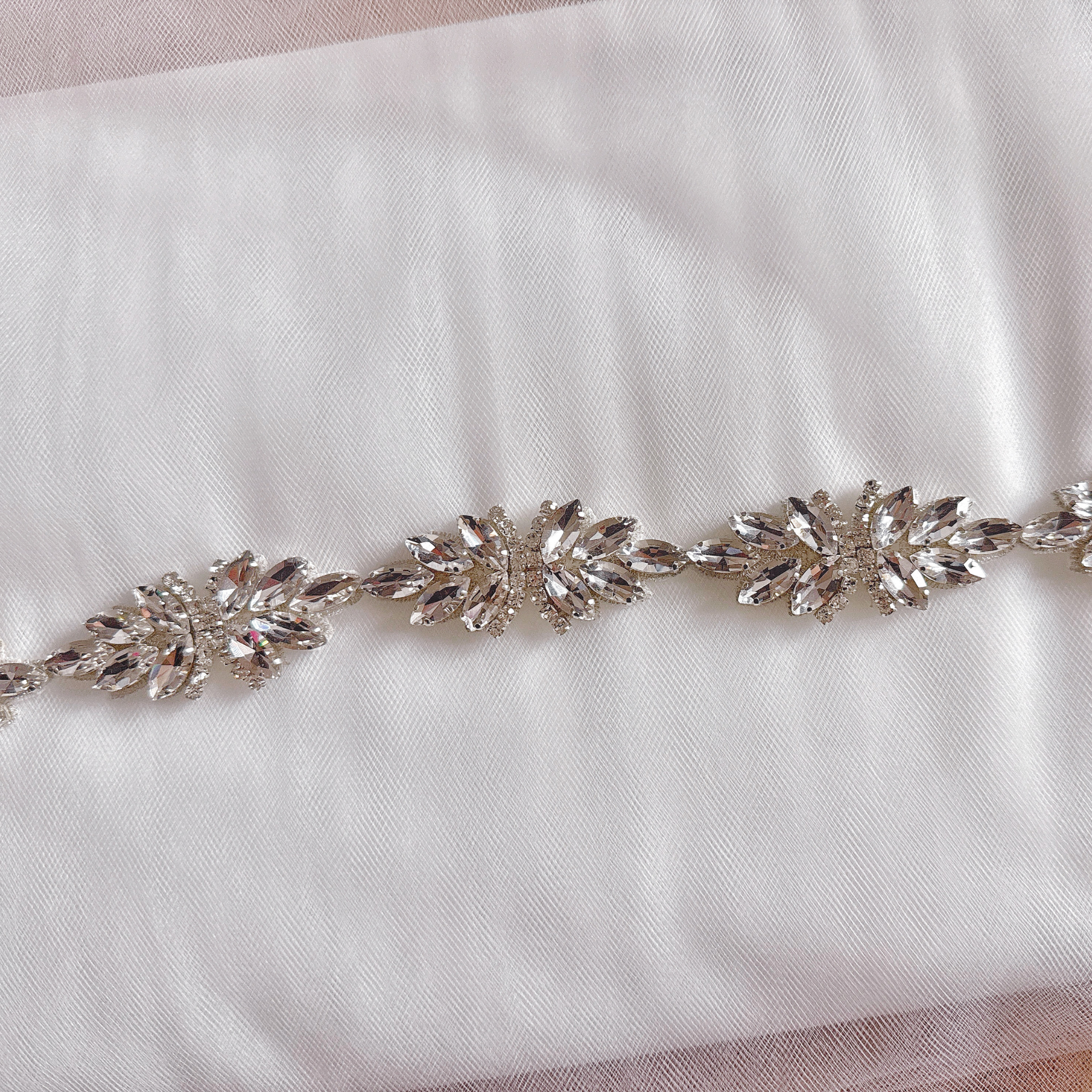 Extreme close-up of the silver beaded bridal belt showing the detailed craftsmanship of the sewn-on crystals and silver threads.
