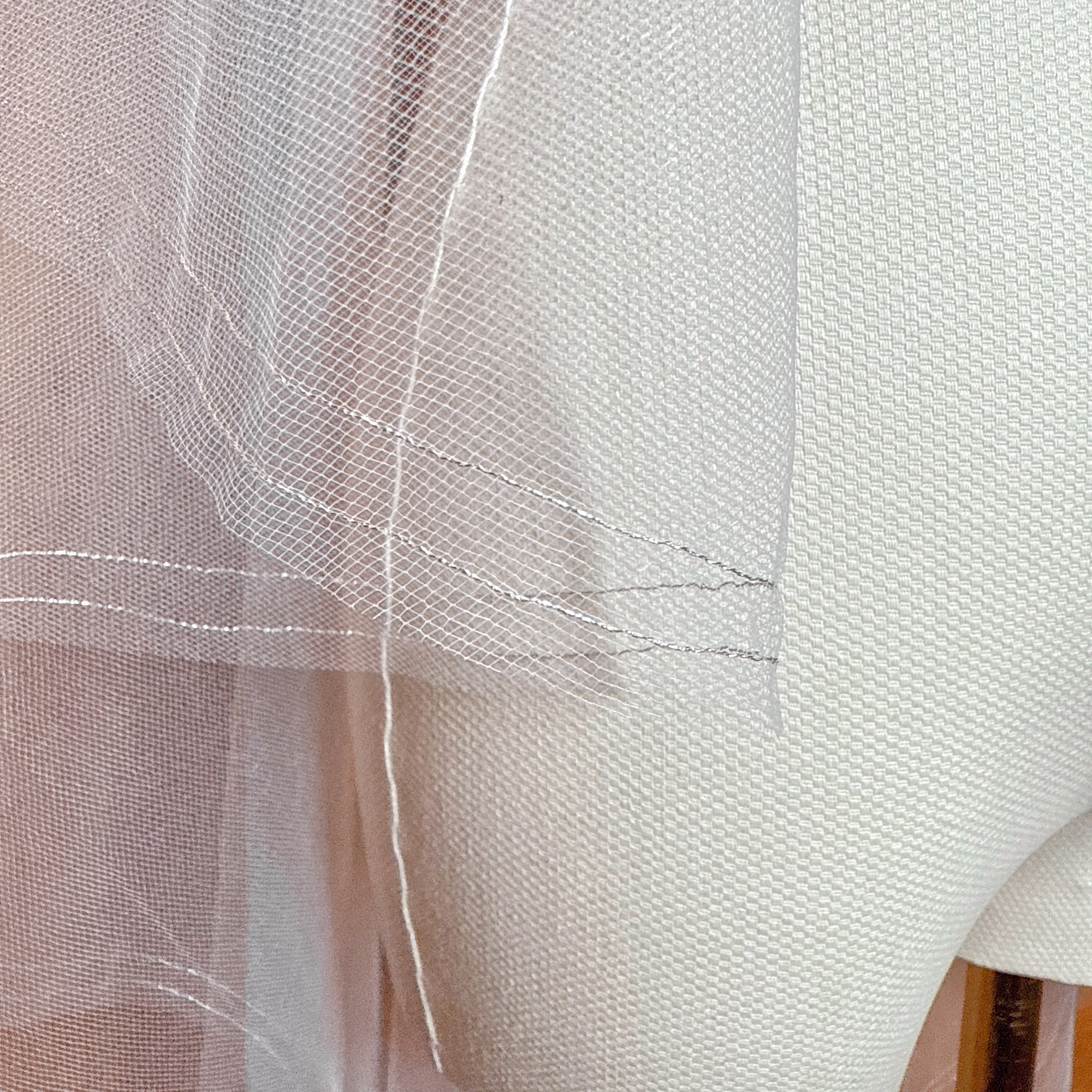 Detailed close-up of the delicate silver metallic edge on a waltz length two tier blusher veil displayed on a mannequin.