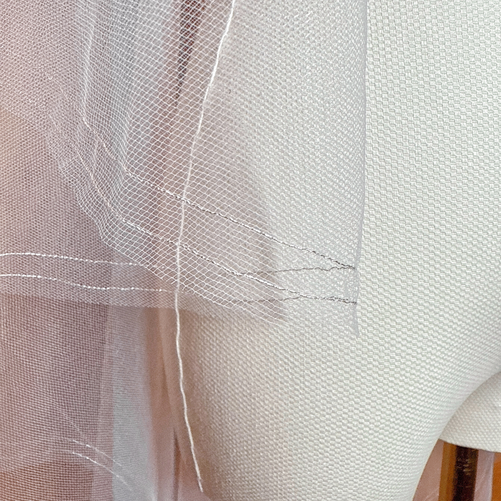 Detailed close-up of the delicate silver metallic edge on a waltz length two tier blusher veil displayed on a mannequin.