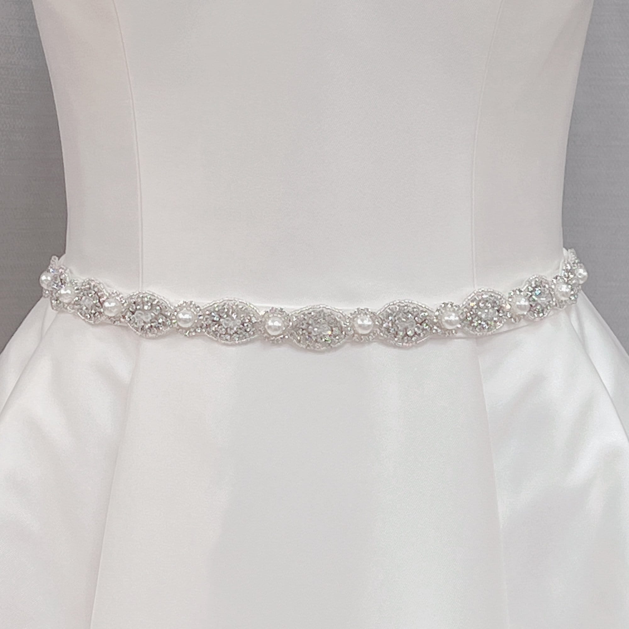 Silver rhinestone and pearl bridal belt displayed on a dress form mannequin to show intricate crystal details.