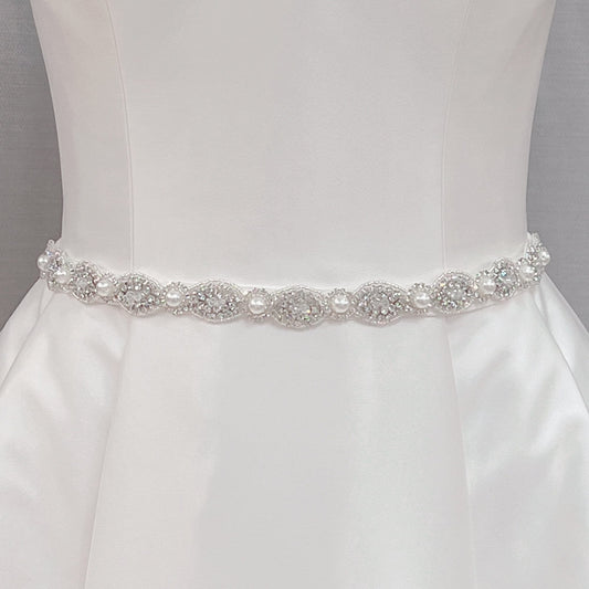 Silver rhinestone and pearl bridal belt displayed on a dress form mannequin to show intricate crystal details.