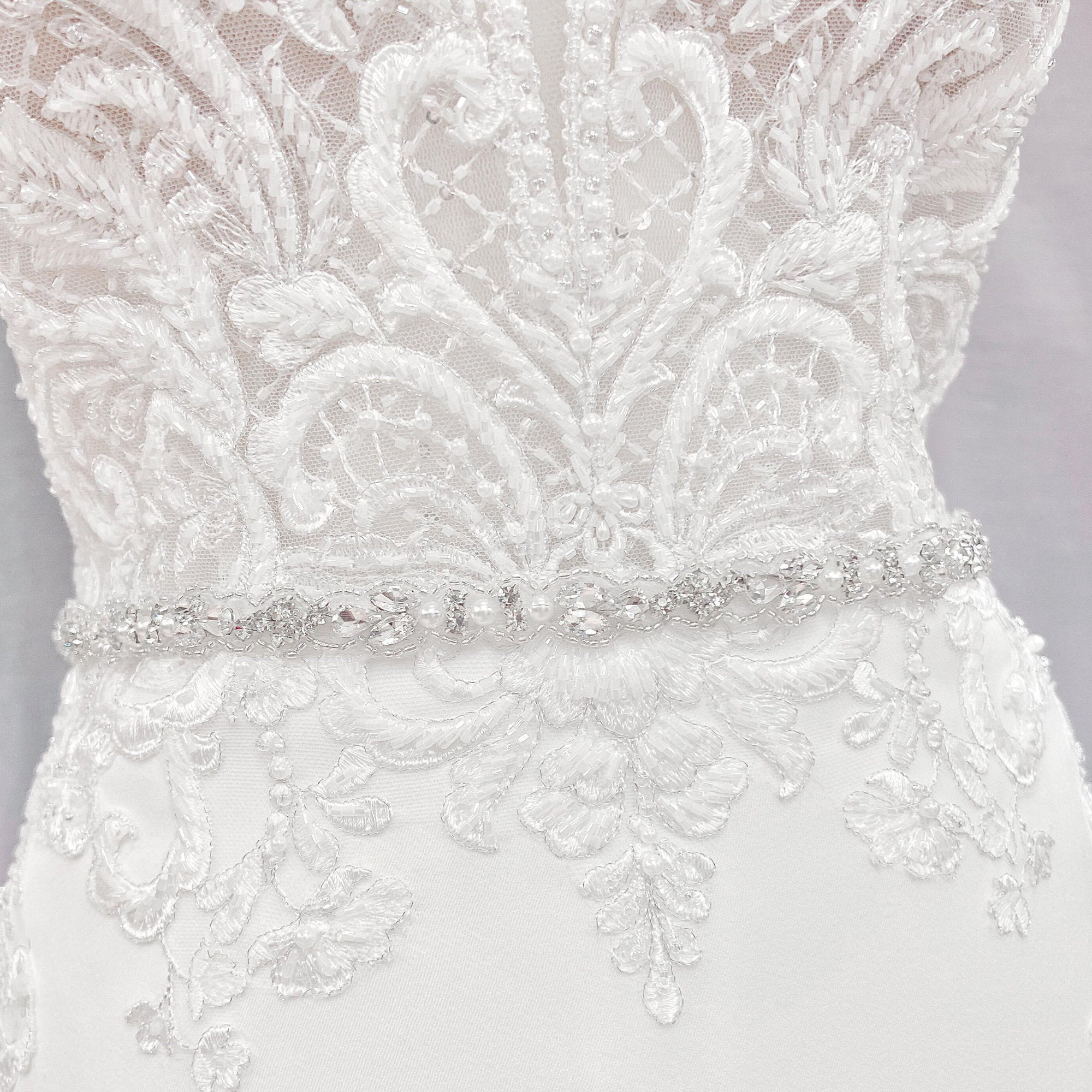 Close-up shot of a silver rhinestone and pearl bridal belt showcasing the intricate crystal patterns and beadwork.