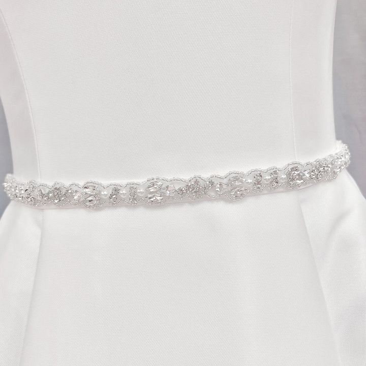 Side profile view of a silver rhinestone and pearl bridal belt highlighting the flush placement and sparkle against a wedding dress fabric.