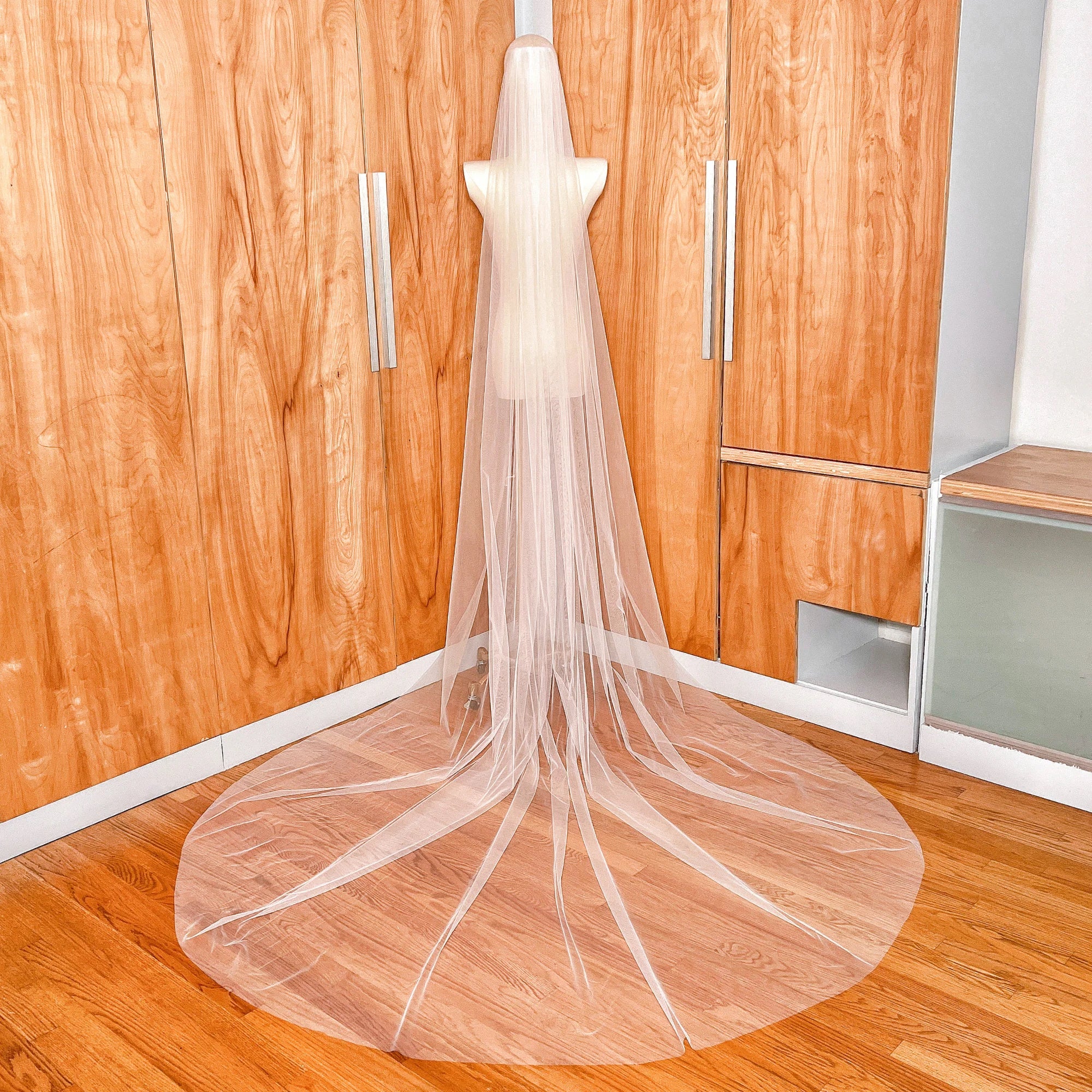 Elegant display of a single-tier cathedral length veil with a modern raw edge draped to show its full 118-inch span.