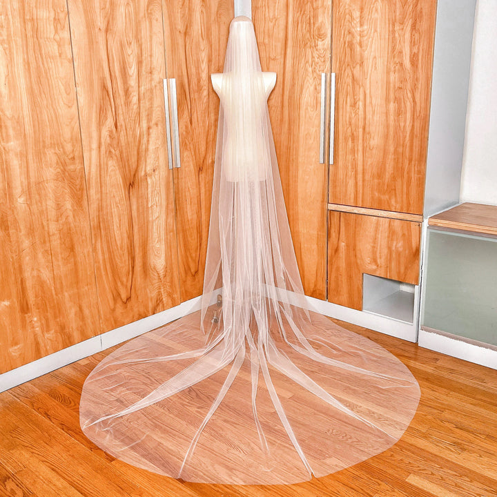 Elegant display of a single-tier cathedral length veil with a modern raw edge draped to show its full 118-inch span.