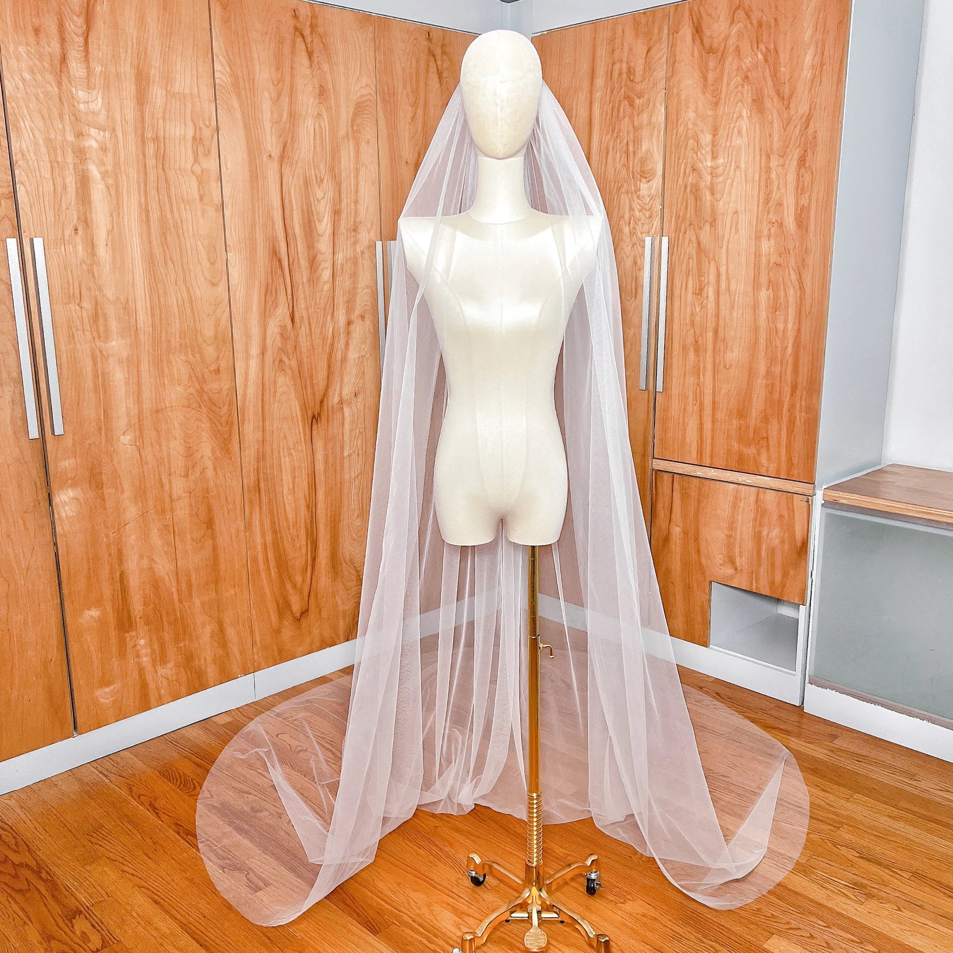 A full-length view of a simple cathedral length raw edge veil made of soft ivory tulle.
