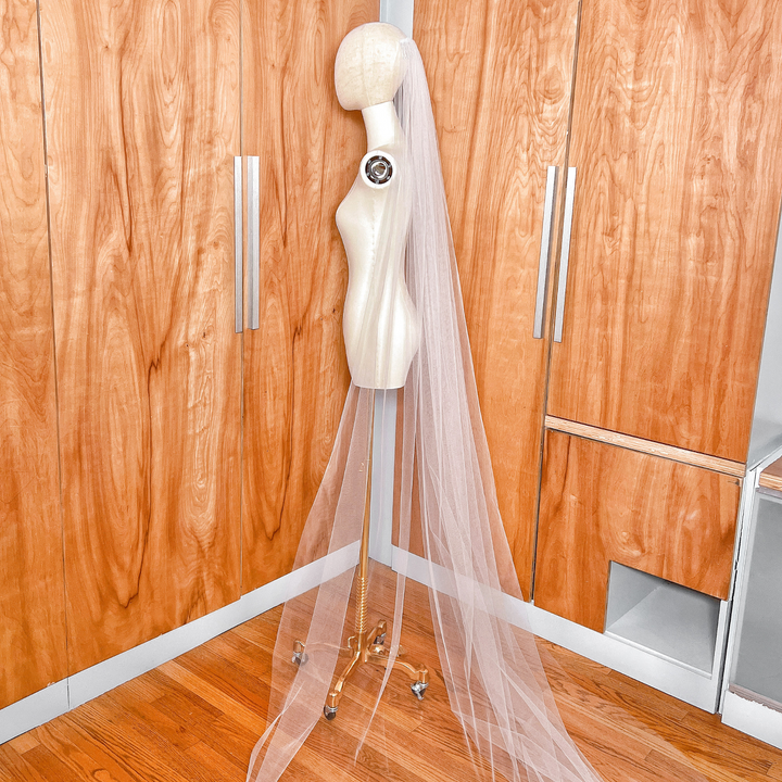 Side profile of a simple cathedral tulle wedding veil with a raw edge, demonstrating how the veil falls and layers over a bridal silhouette.