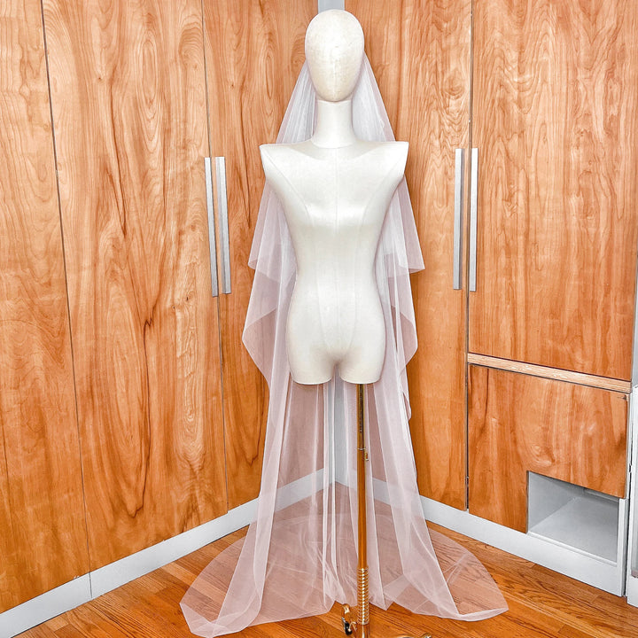 Full-length view of a simple two-tier wedding veil in chapel length, showing the blusher layer and the main tier's graceful drape.