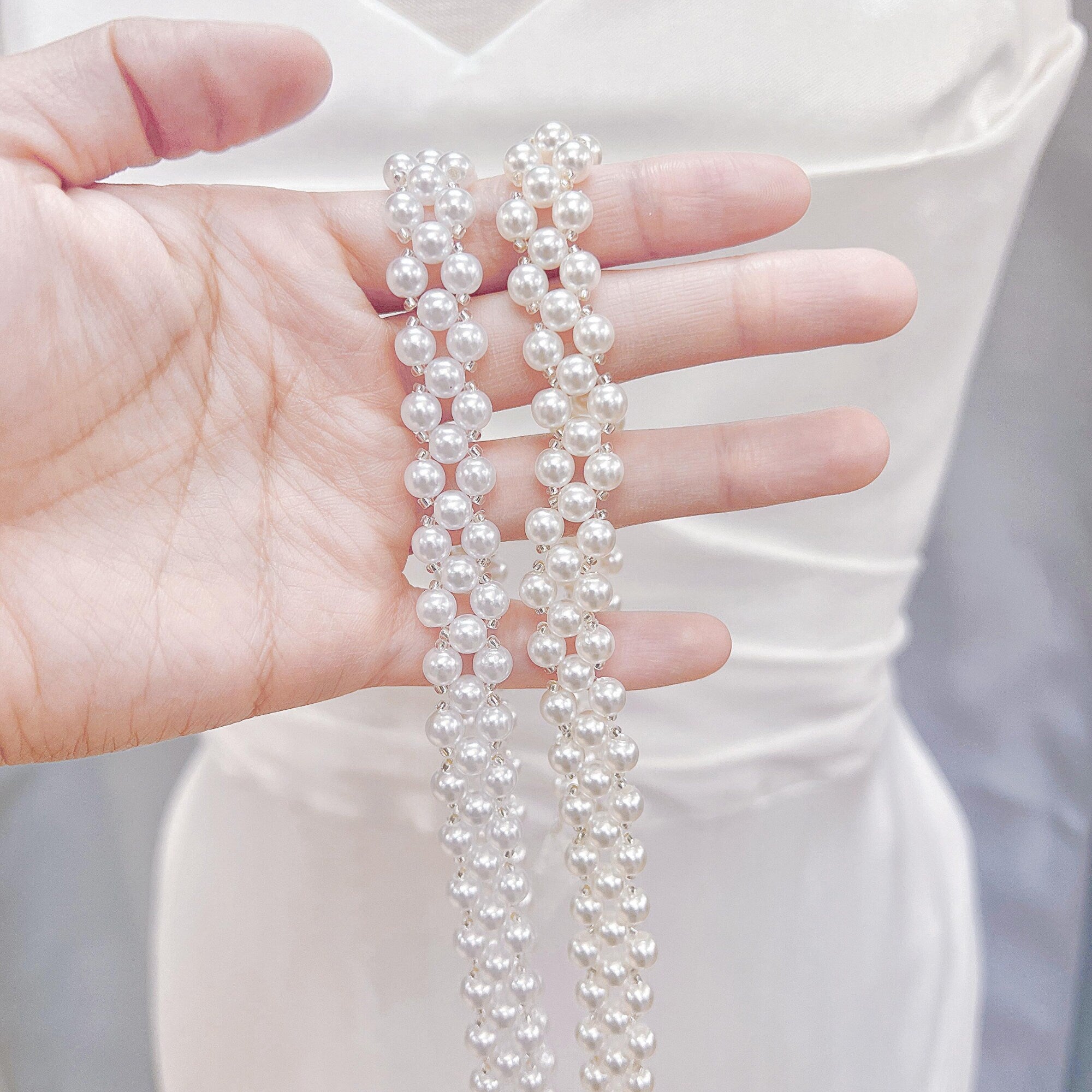 Close-up of a simple pearl bridal belt with delicate white pearls on a organza ribbon.