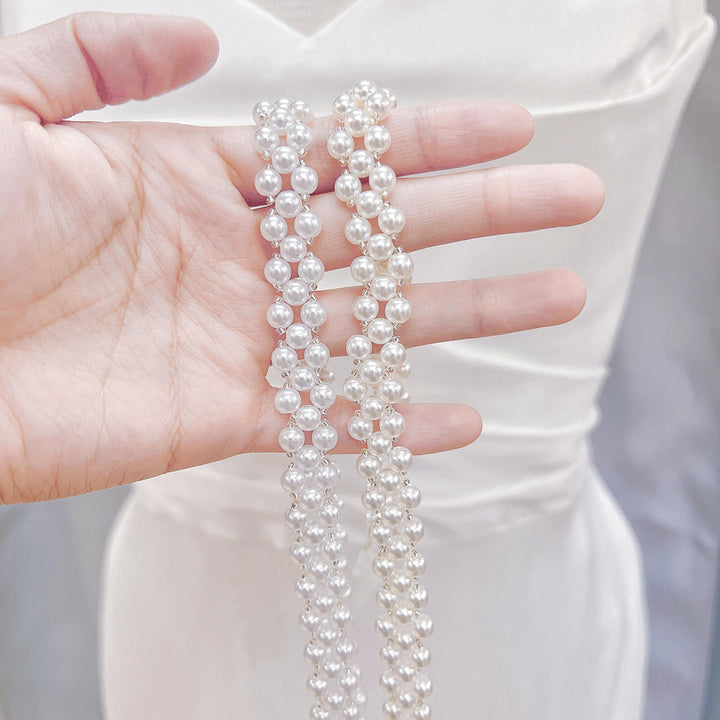 Close-up of a simple pearl bridal belt with delicate white pearls on a organza ribbon.
