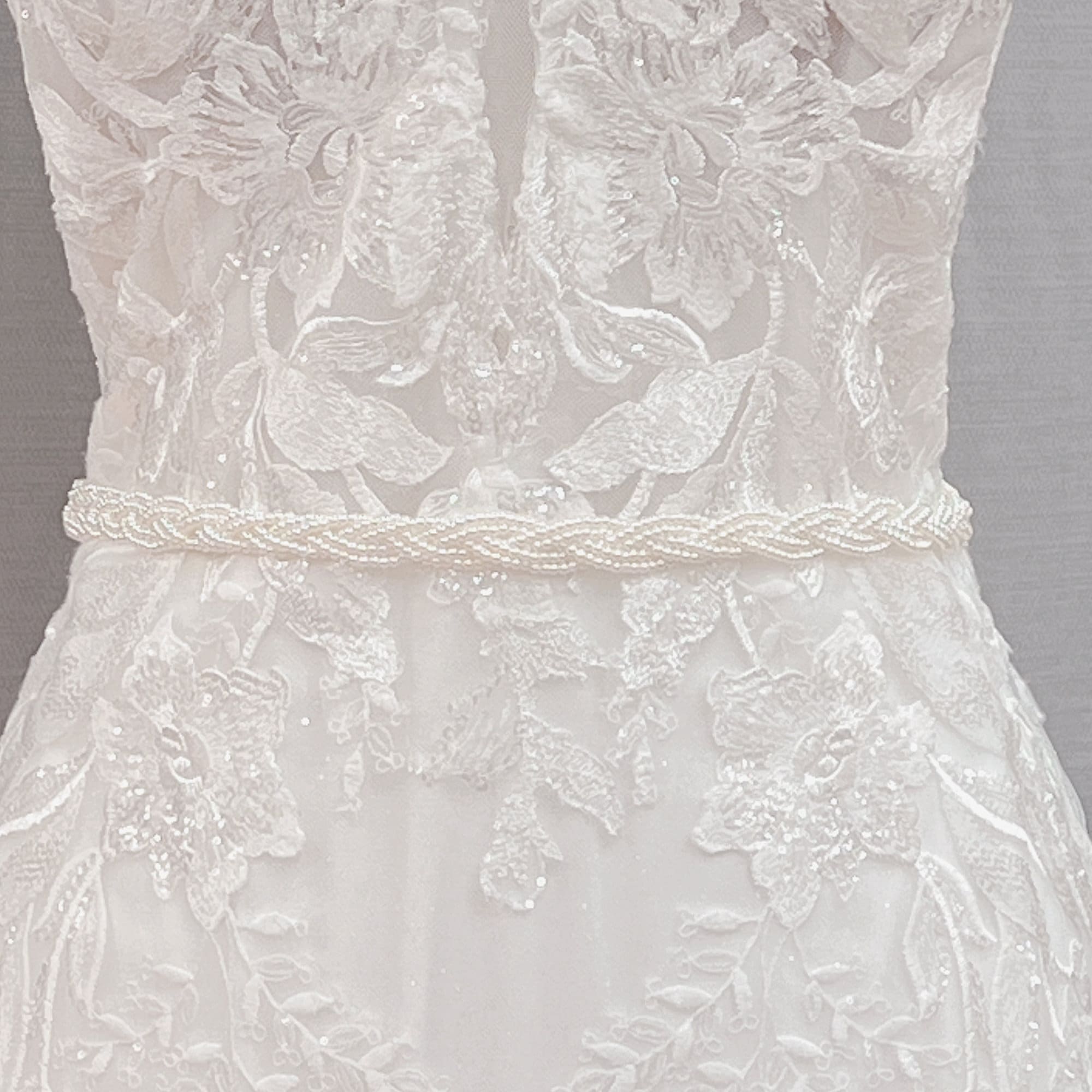 Close-up details of the Simple Pearl Bridal Belt and minimalist white wedding sash on a studio mannequin.