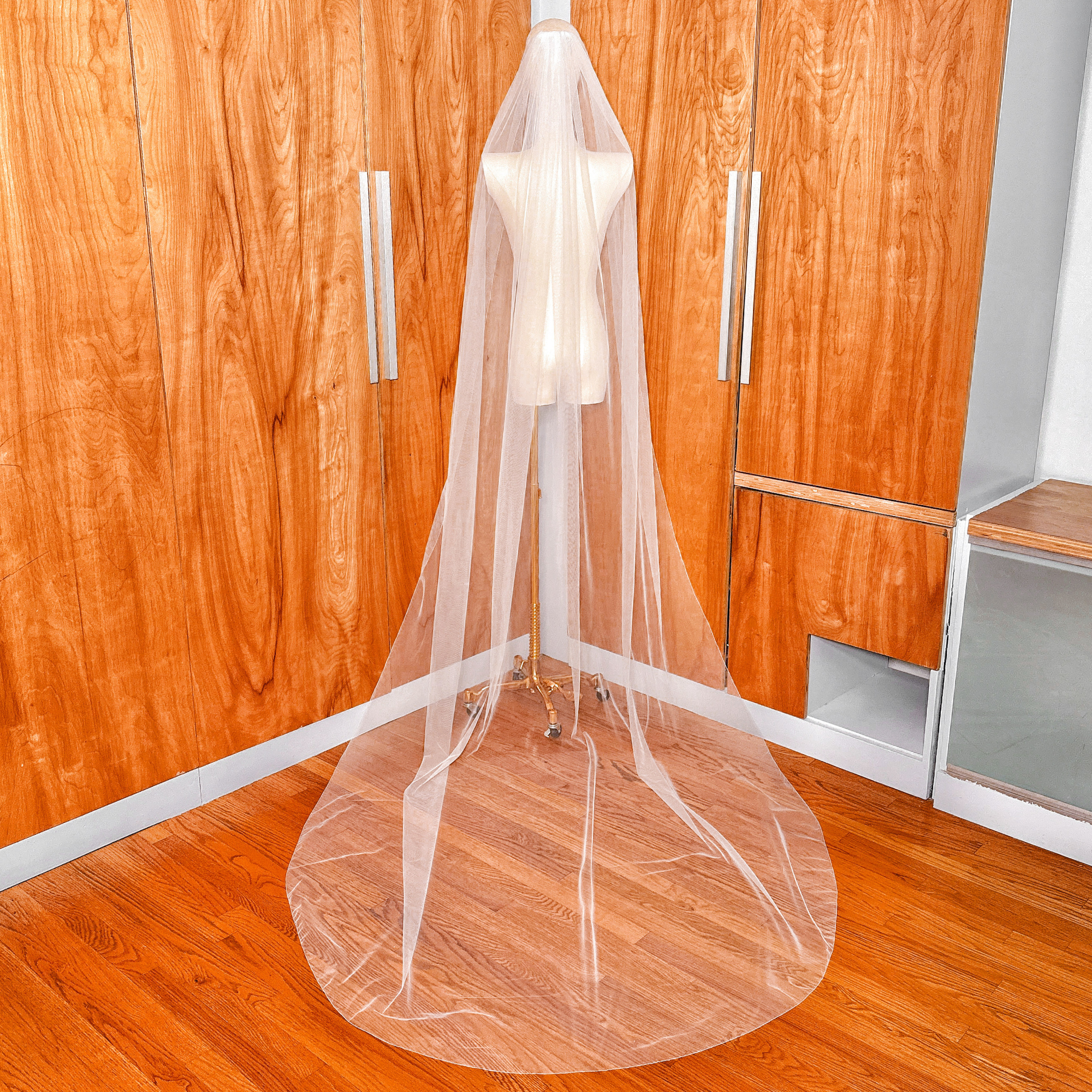 Full back view of a cathedral length simple pencil edge wedding veil on a mannequin torso.