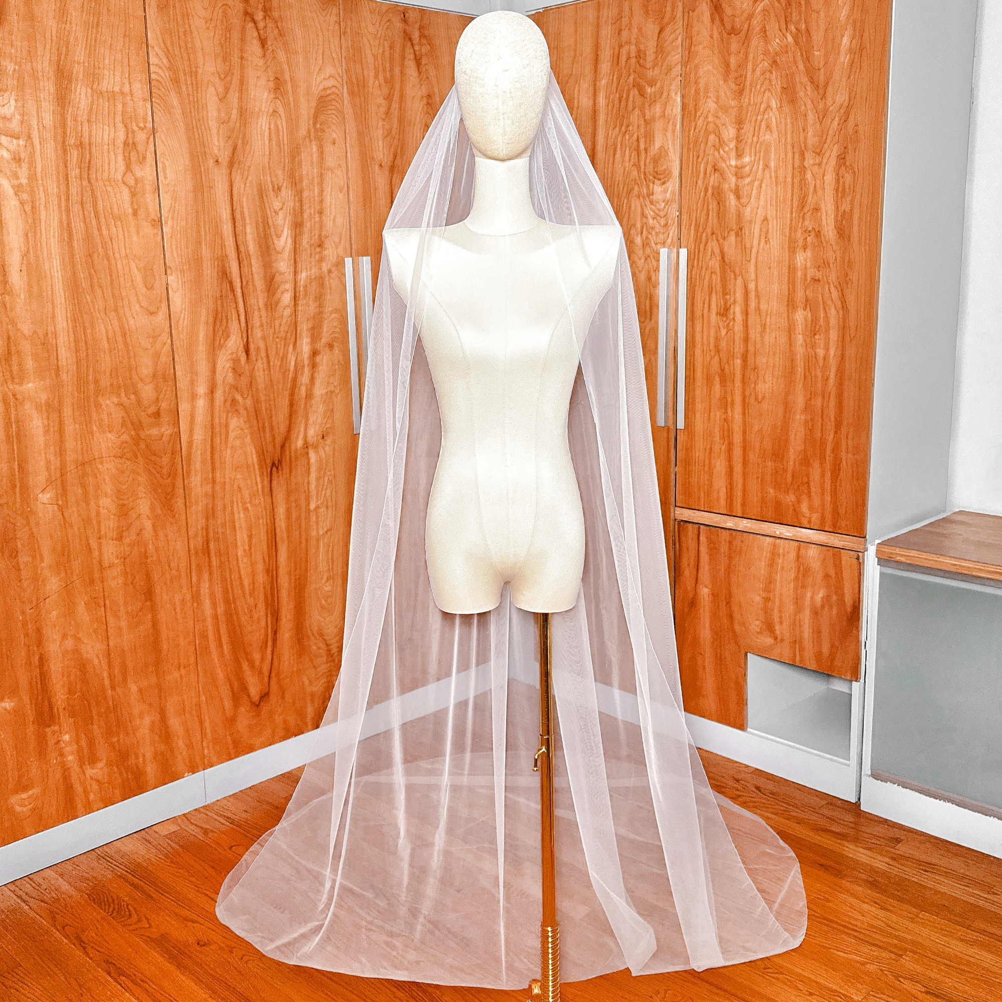 Long cathedral length simple pencil edge wedding veil flowing down from a display mannequin.