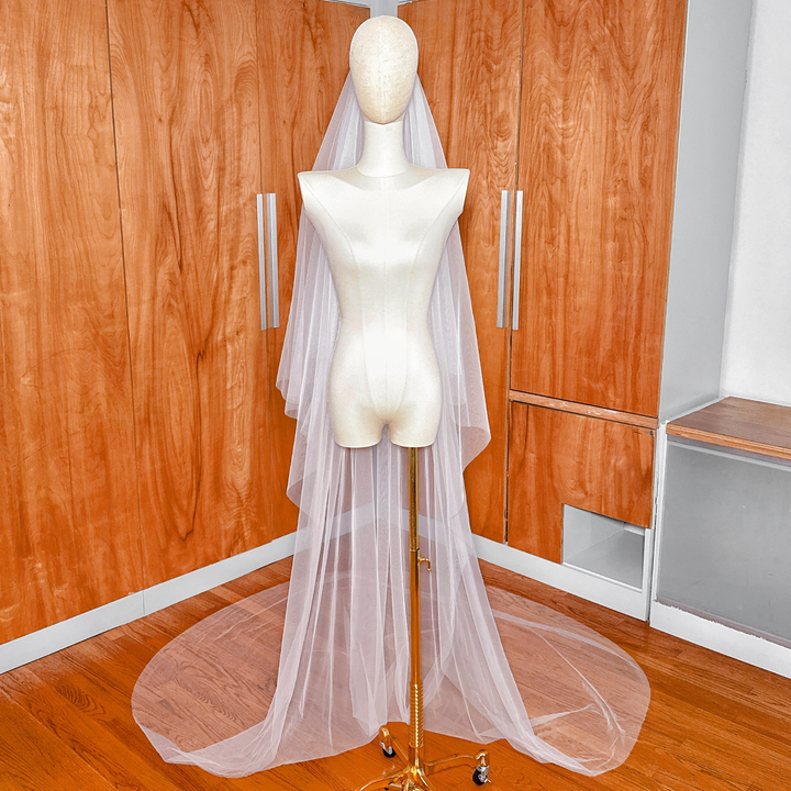 Wide shot of a simple soft two-tier cathedral veil sweeping across the floor behind a mannequin.