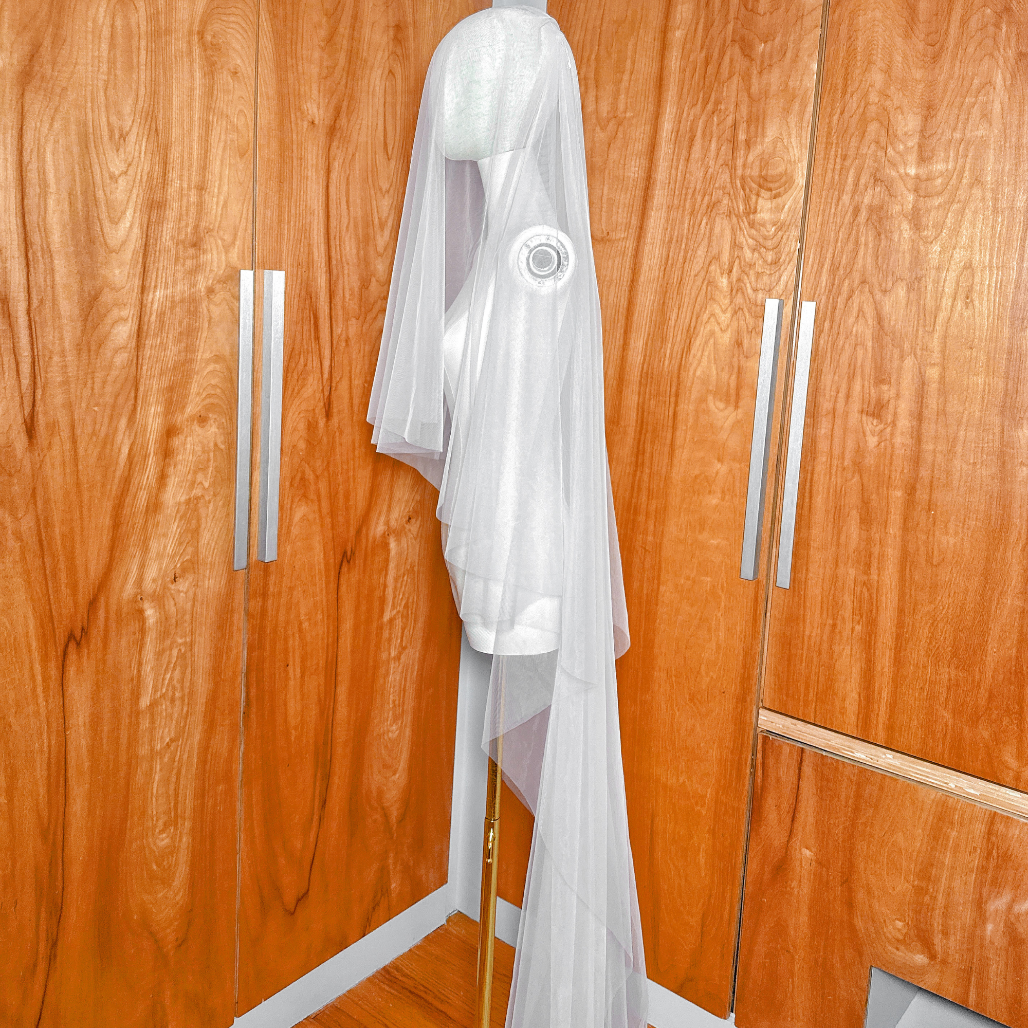Cathedral length simple soft two-tier veil on a mannequin with the top tier draped forward as a blusher.