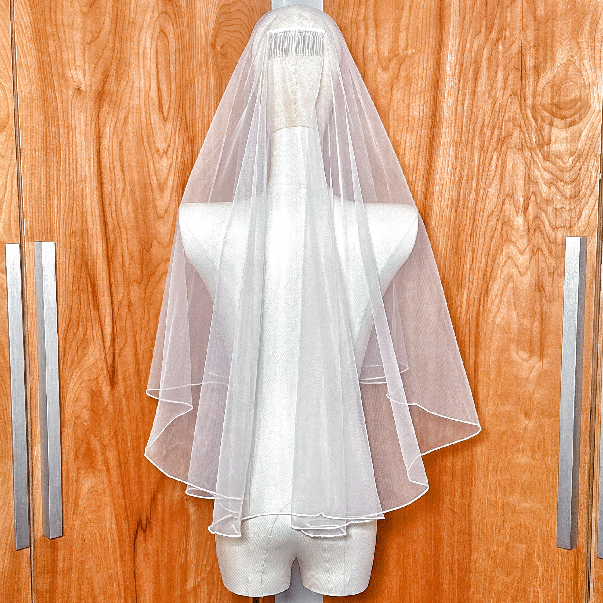 Rear view of an elbow length simple two tier wedding veil with a clean pencil edge finish.