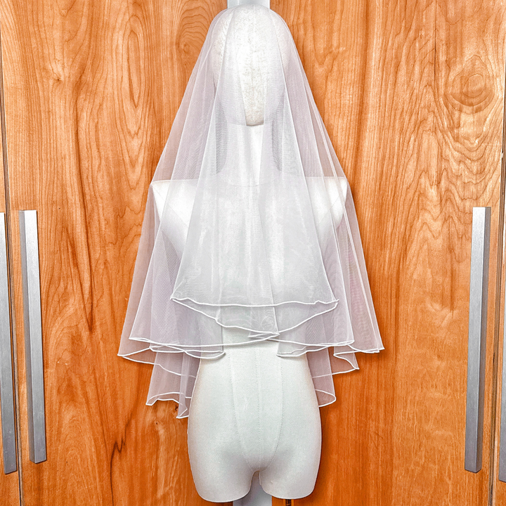 Front view of a simple two tier wedding veil with pencil edge cut to elbow length.