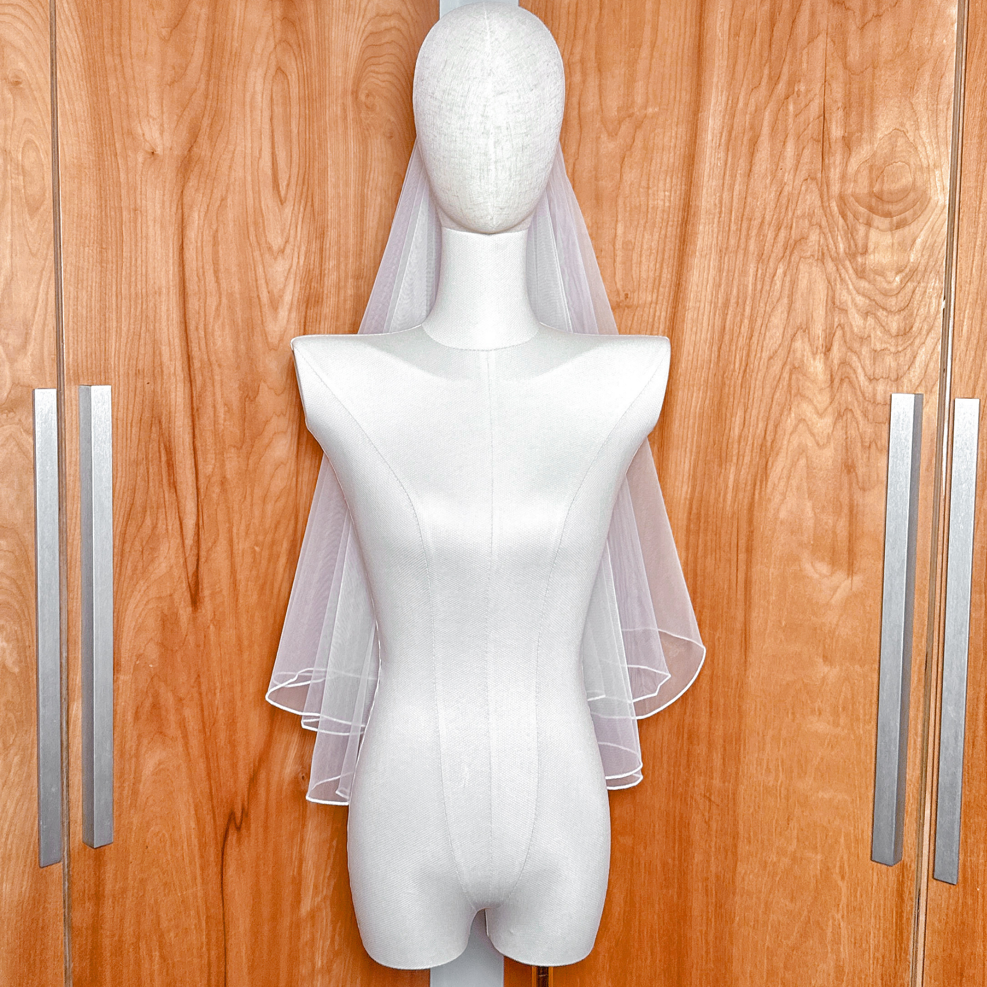 Bridal tulle texture of a simple two tier wedding veil with pencil edge in elbow length.