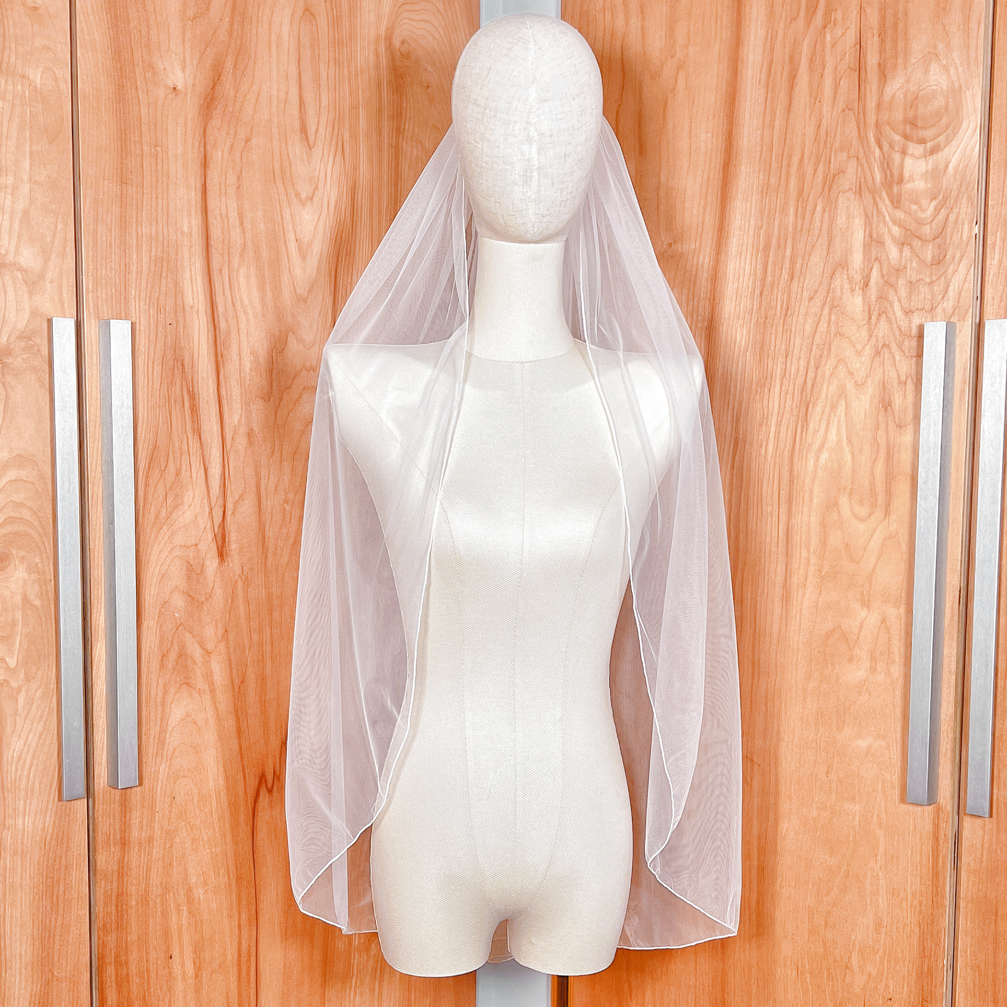 Single tier pencil edge wedding veil in fingertip length displayed on a bridal mannequin.