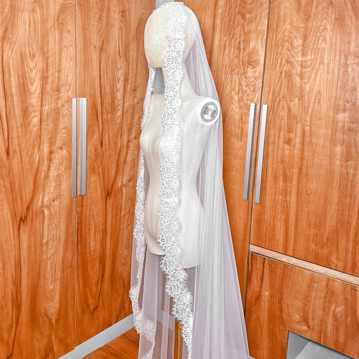 Soft ivory Chantilly lace mantilla veil in cathedral length displayed on a bridal mannequin.