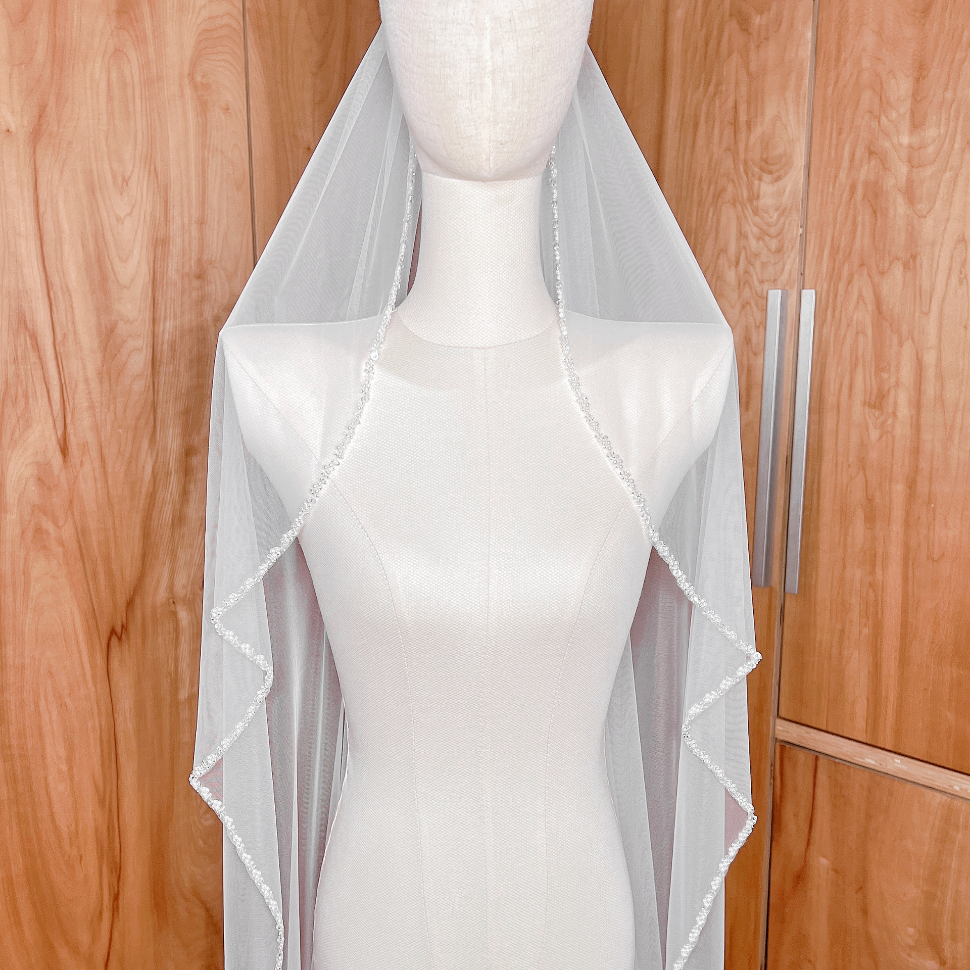 Elegant cathedral length wedding veil with a cascading beaded edge, a timeless accessory for a bridal look.