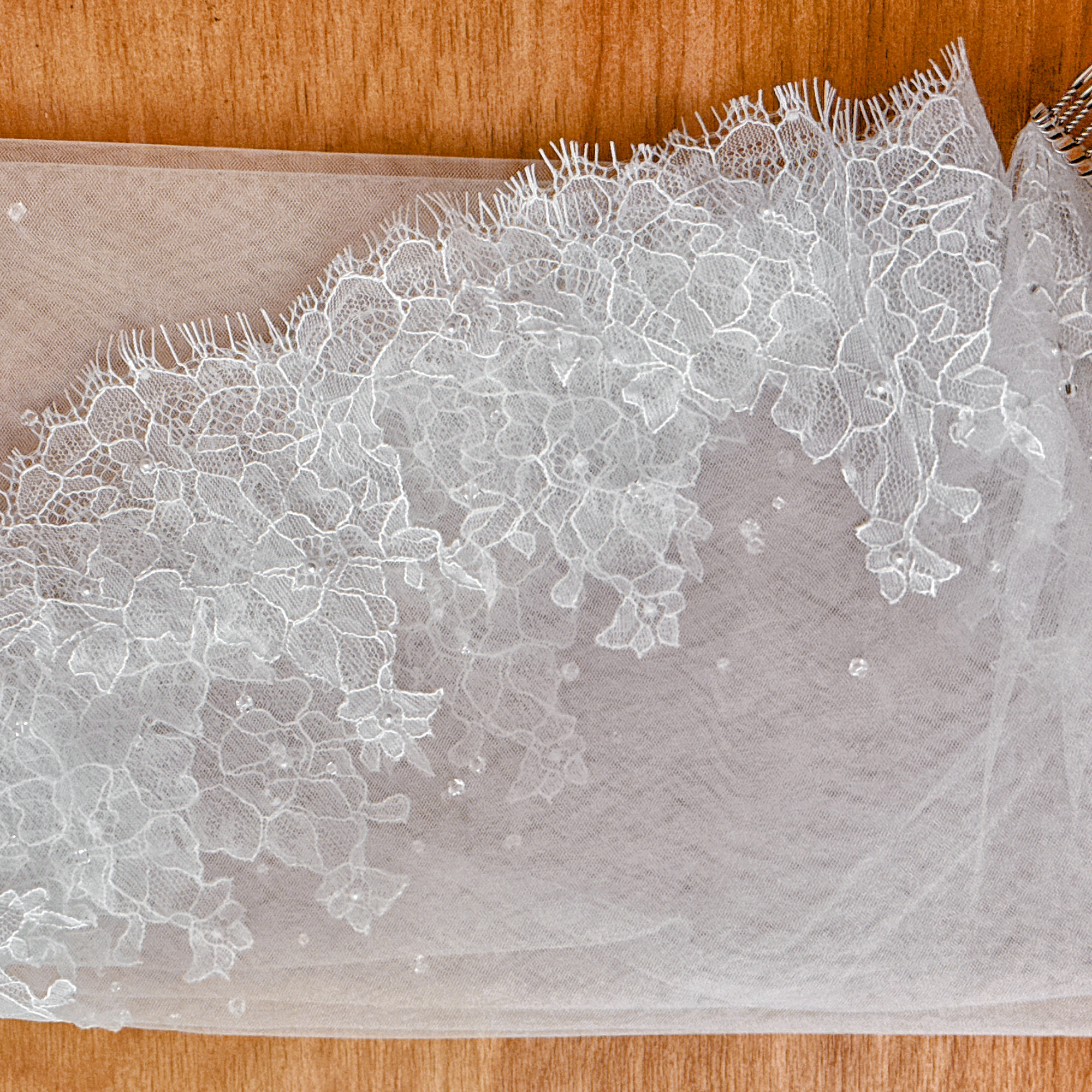 Soft bridal illusion tulle and scalloped lace trim of an elbow-length mantilla veil on a mannequin.