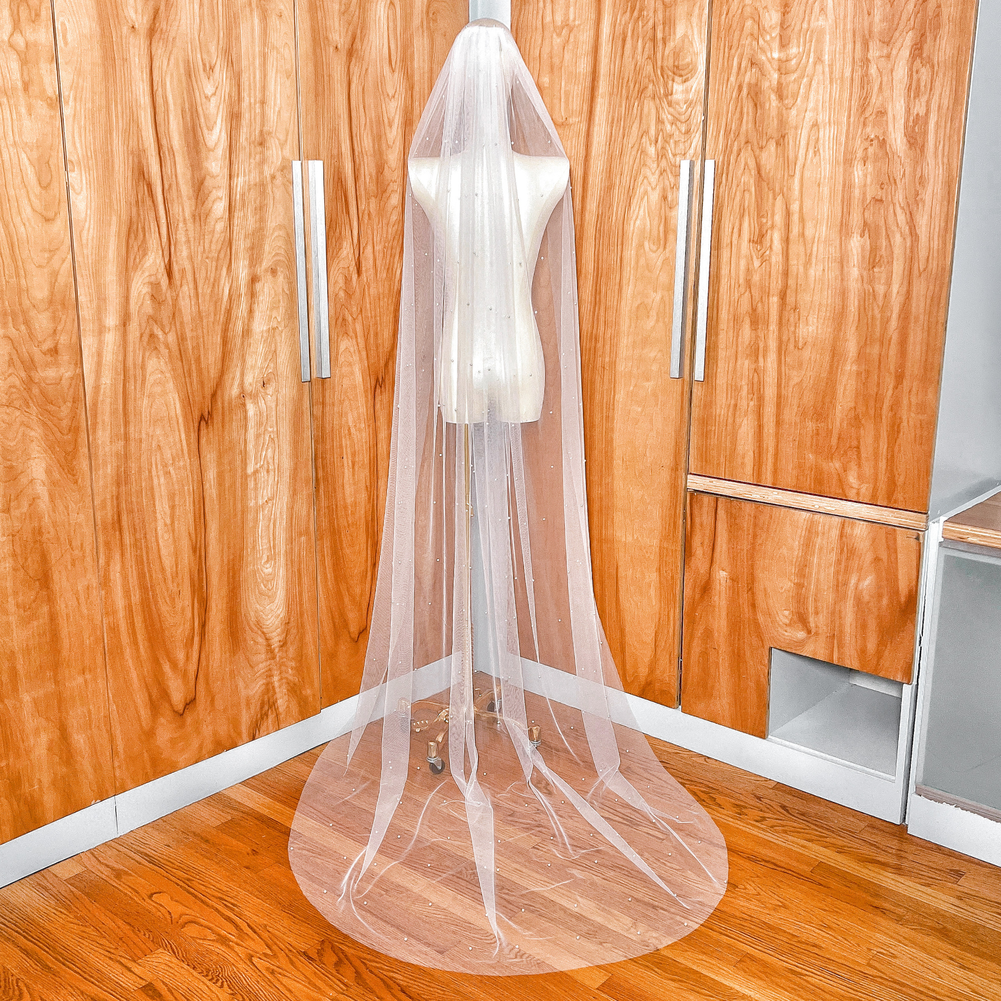Rear view of a scattered pearl wedding veil in chapel length, highlighting the airy movement of the soft tulle fabric.