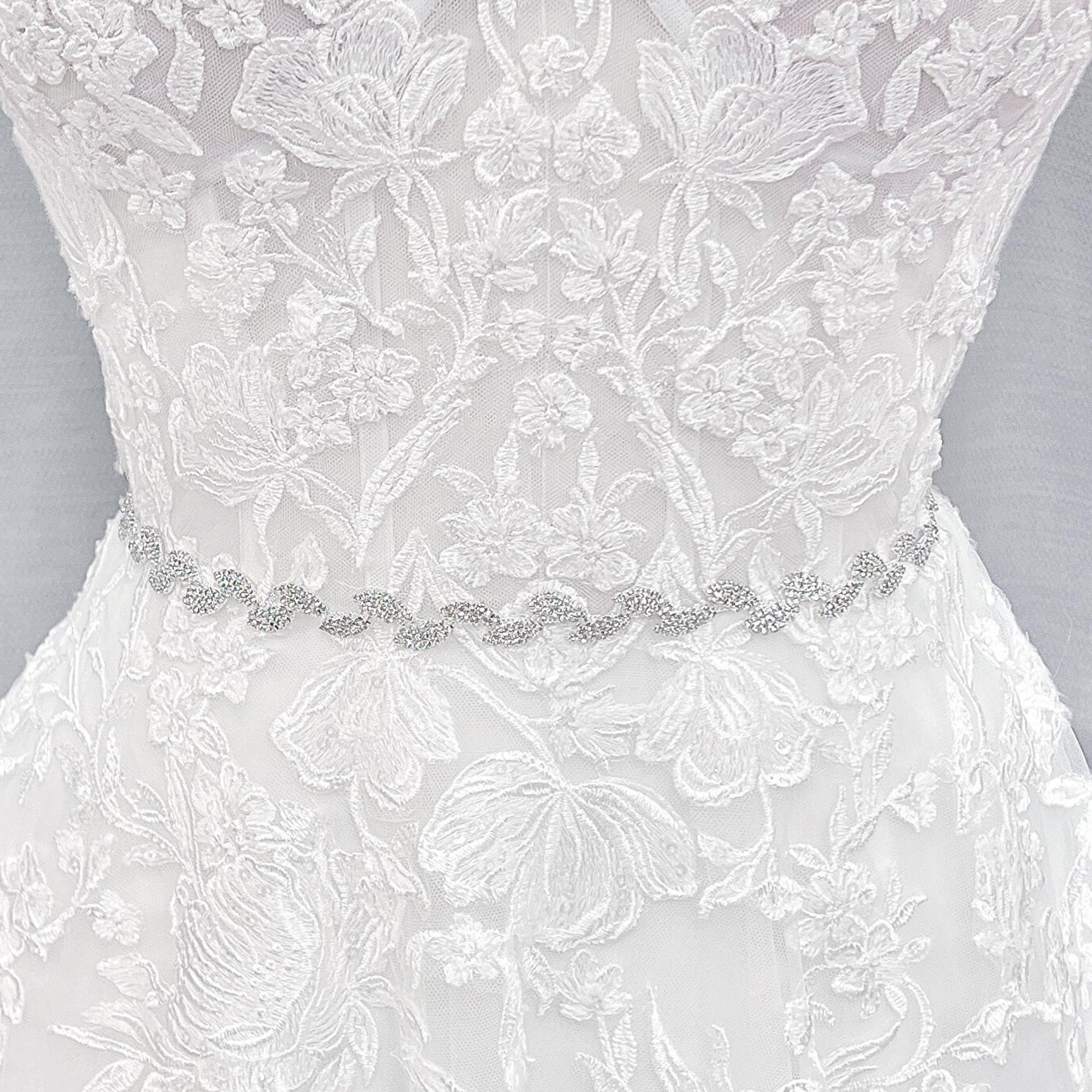 Close-up shot of a thin silver crystal bridal belt with intricate rhinestone beadwork.