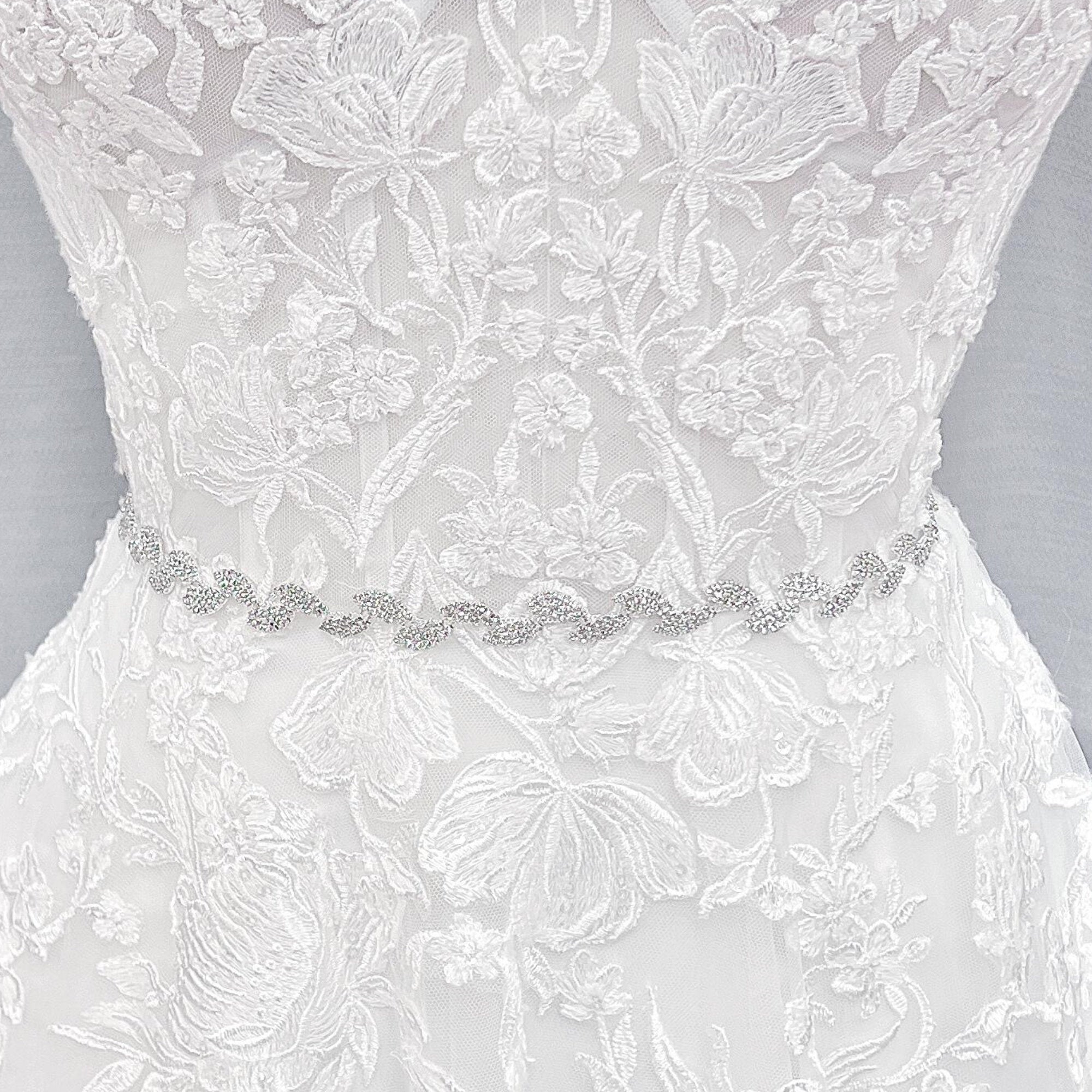 Close-up shot of a thin silver crystal bridal belt with intricate rhinestone beadwork.