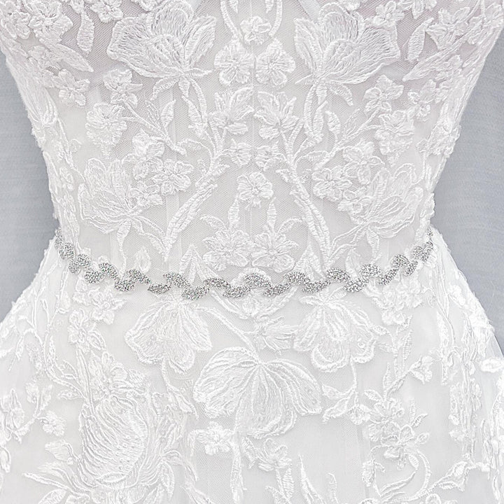 Close-up shot of a thin silver crystal bridal belt with intricate rhinestone beadwork.
