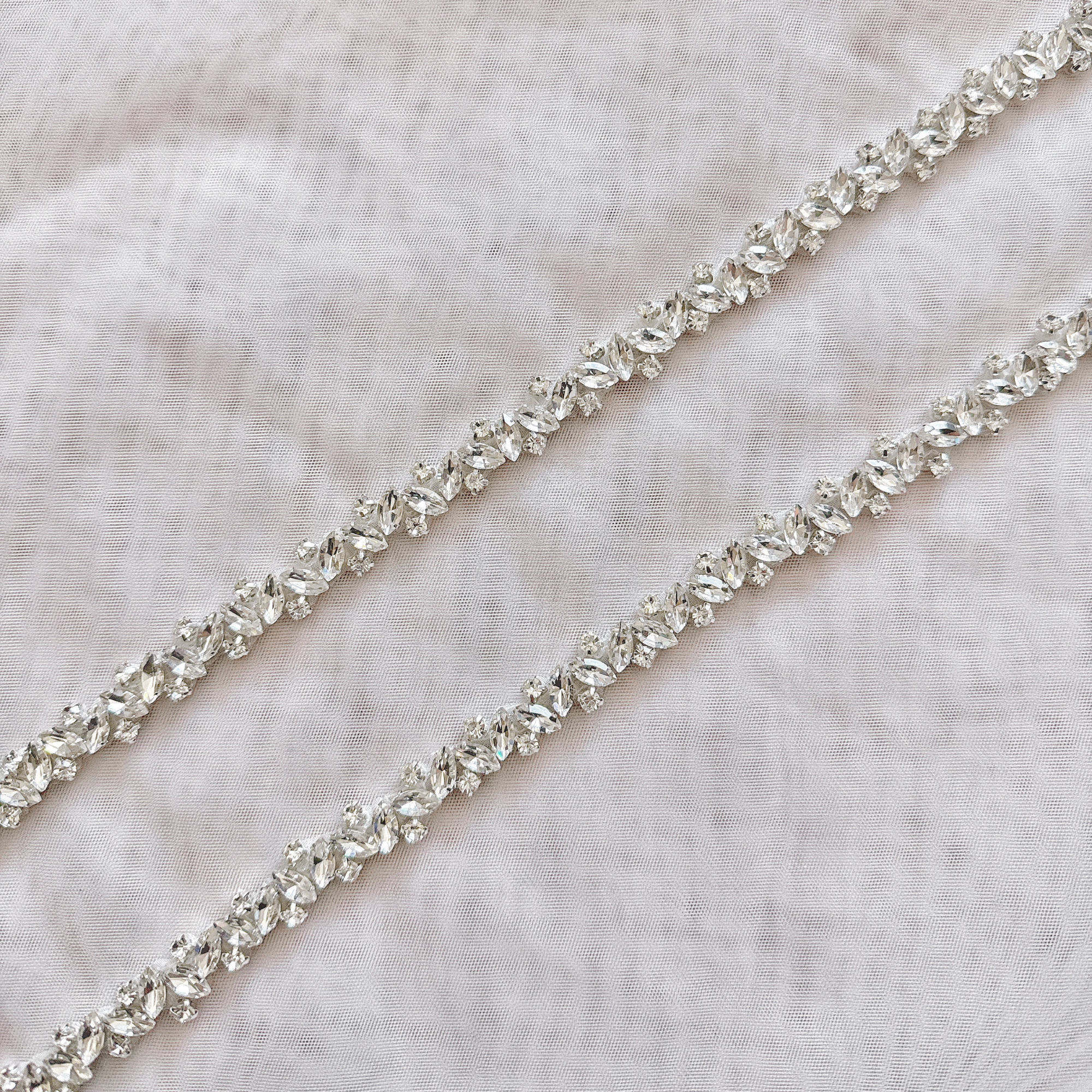 Close-up detail of a thin silver rhinestone bridal belt with intricate crystal beadwork.