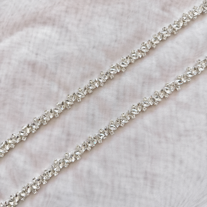 Close-up detail of a thin silver rhinestone bridal belt with intricate crystal beadwork.