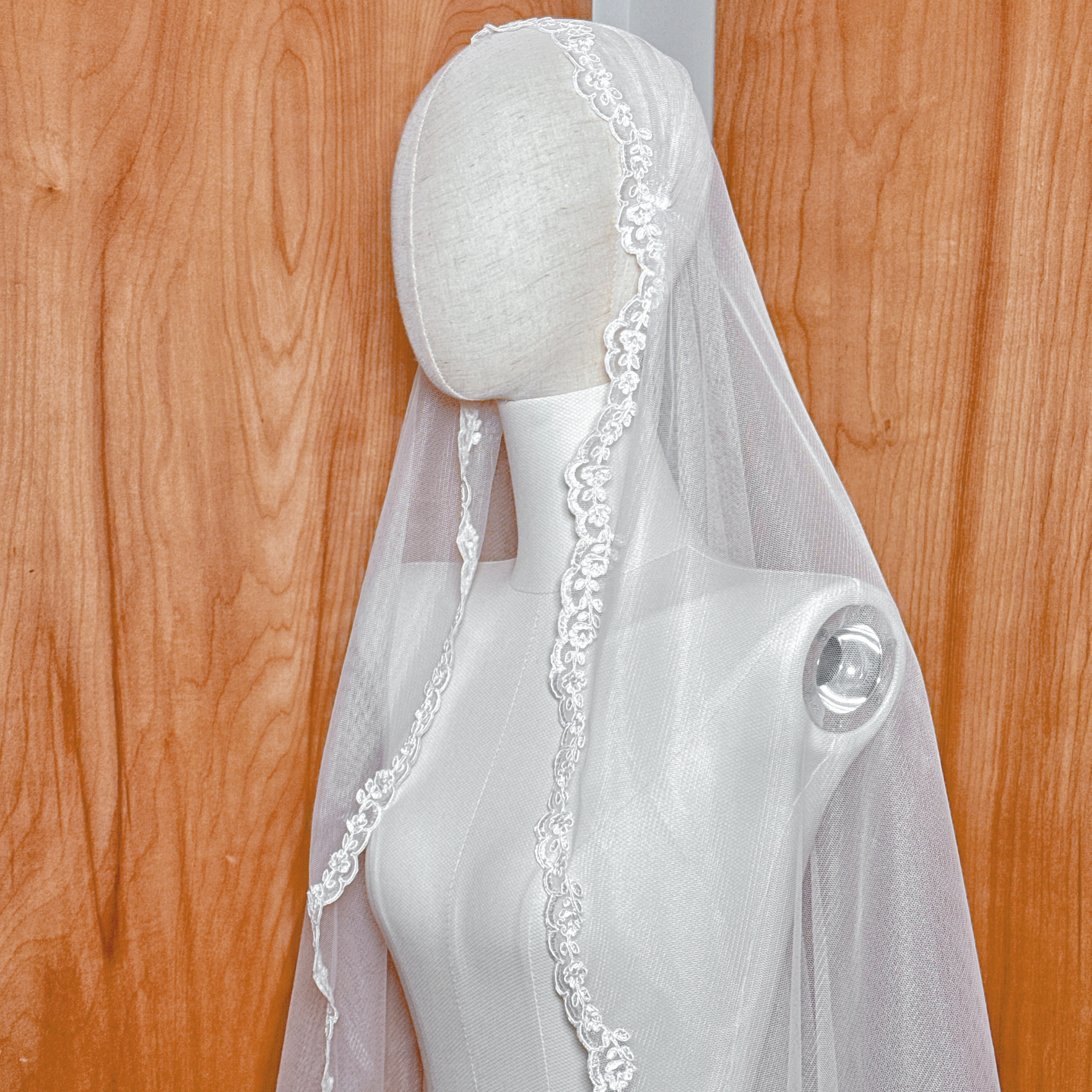 Close shot of an ivory Alençon lace Juliet cap veil on a mannequin to show fingertip proportions.
