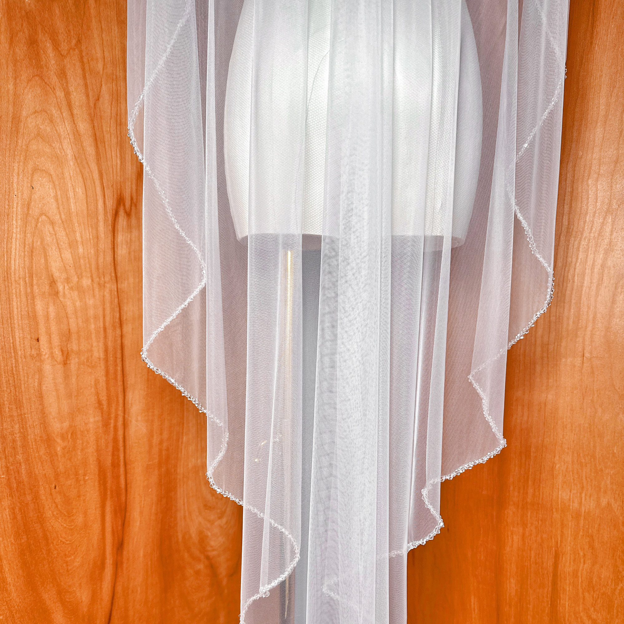 Traditional waltz length mantilla wedding veil featuring a delicate crystal-embellished border.