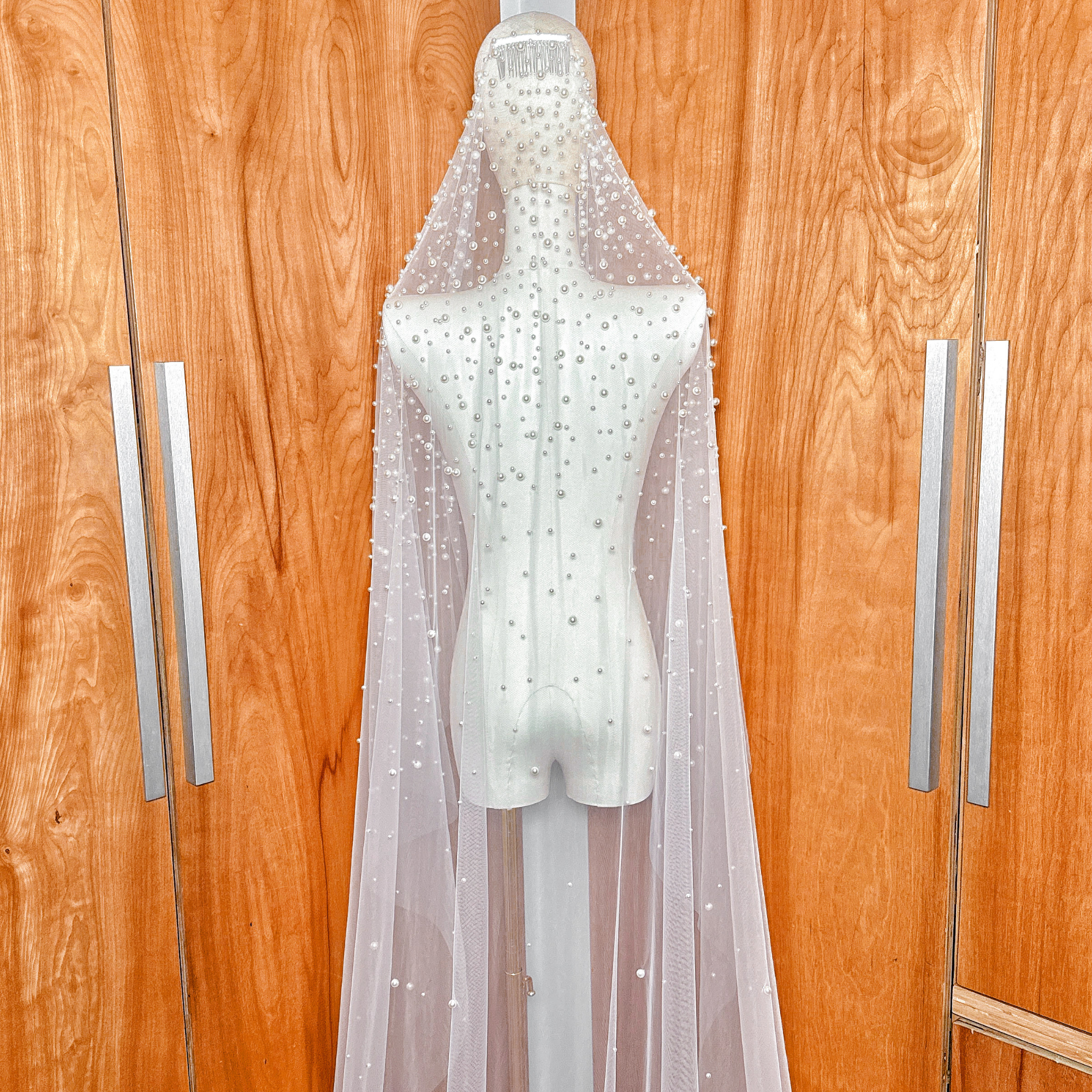 Spanish-style cathedral length pearl studded mantilla wedding veil shown on a bridal mannequin.