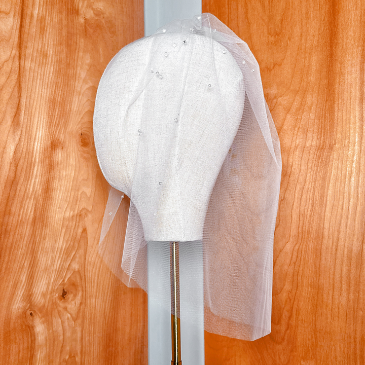 Back view of the gathering on a tulle birdcage wedding veil with rhinestones and pearls.