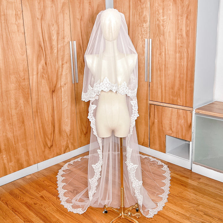 Two tier Alençon lace wedding veil with a sheer blusher shown in cathedral length on a bridal mannequin.
