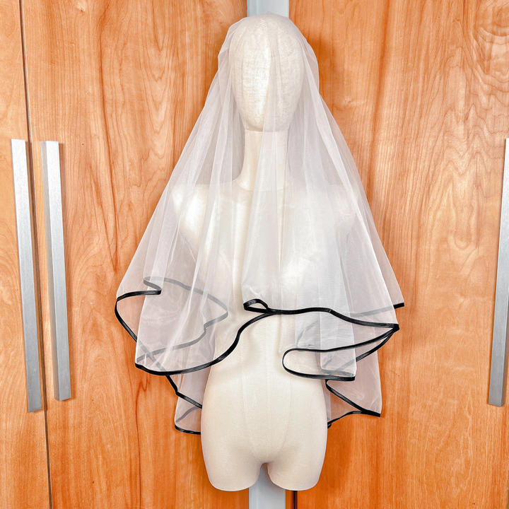 Two-tier black ribbon edge wedding veil in fingertip length displayed on a bridal mannequin.