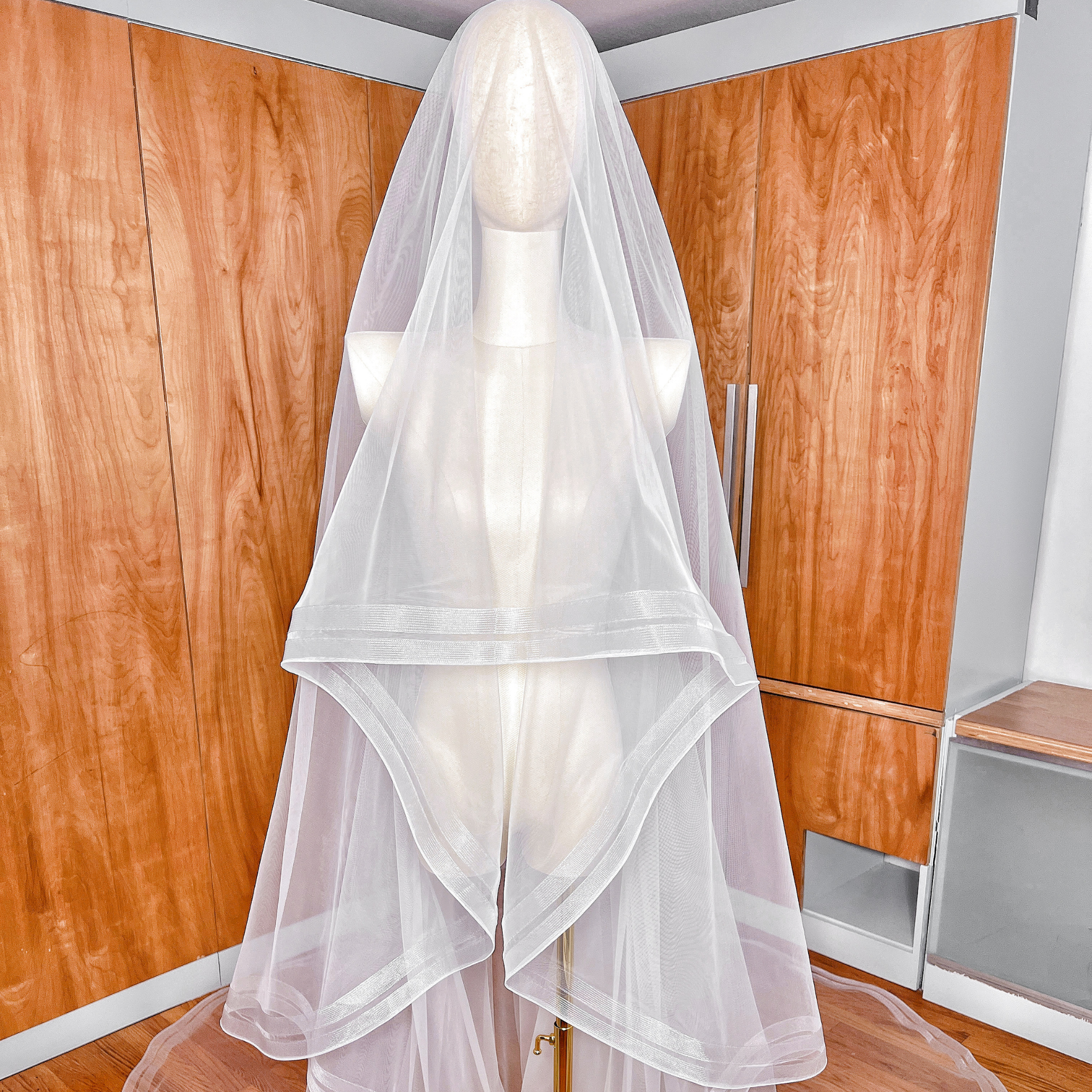 A mannequin showcasing the volume and drape of a two tier cathedral veil with double horsehair edging.