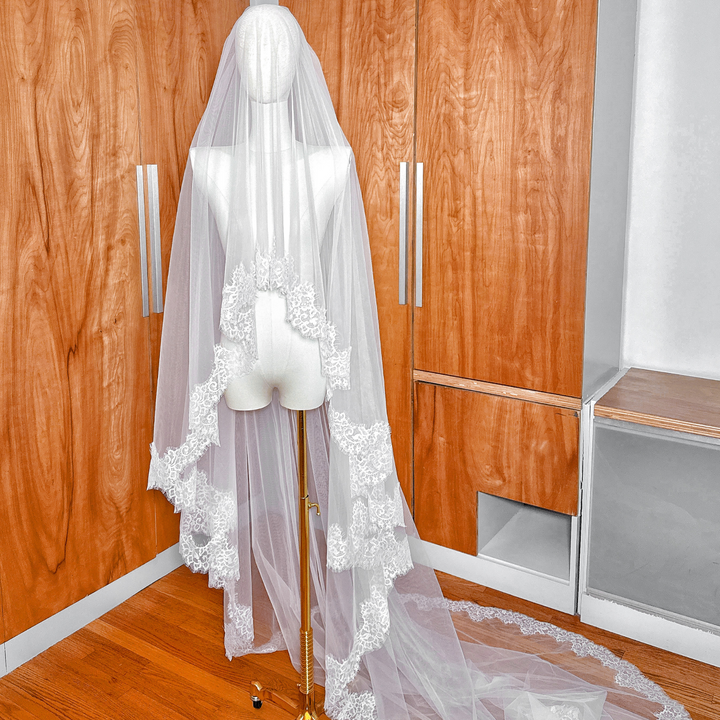 Two tier Chantilly lace trim veil with a blusher layer in cathedral length on a mannequin.