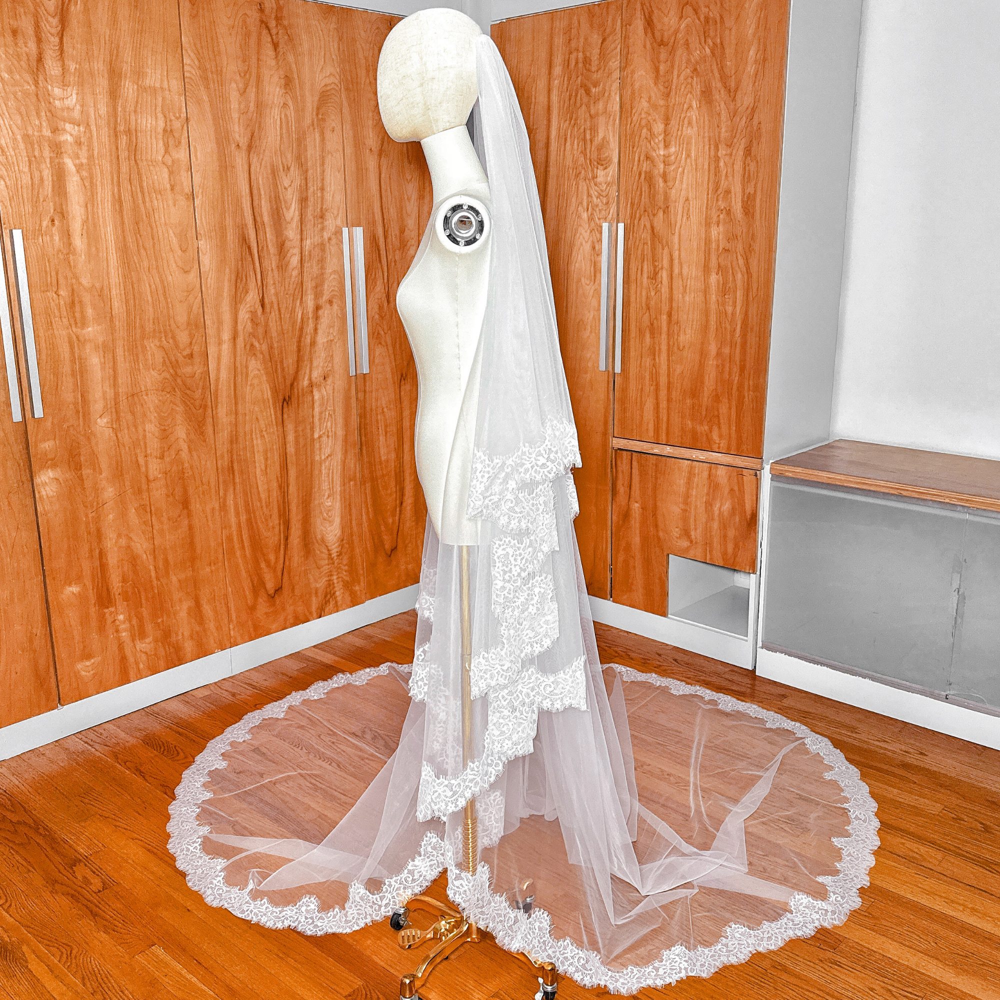 Side profile of a mannequin wearing a two tier Chantilly lace trim veil in cathedral length.