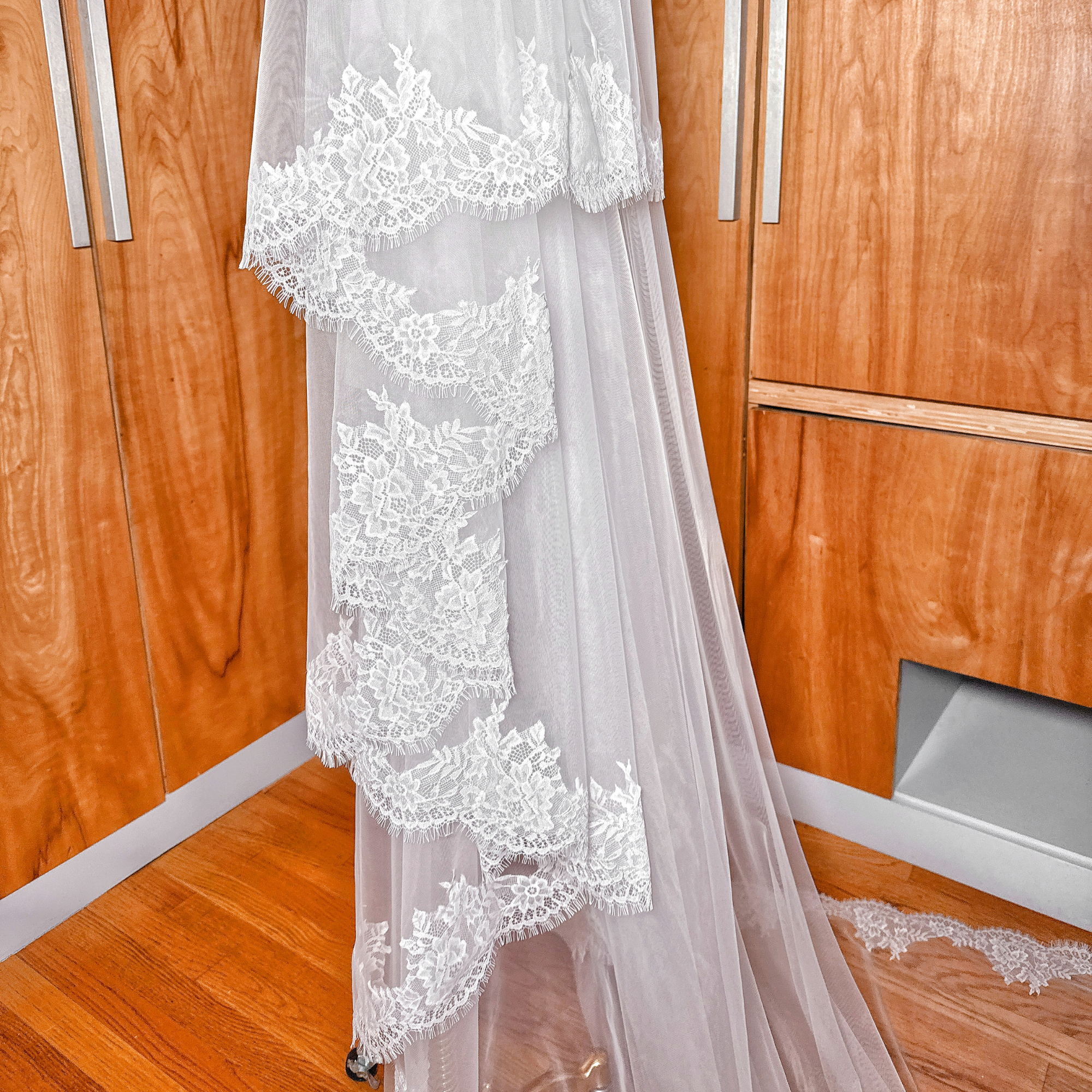 Detailed view of the scalloped Chantilly lace border on a two tier cathedral length bridal veil displayed on a mannequin.